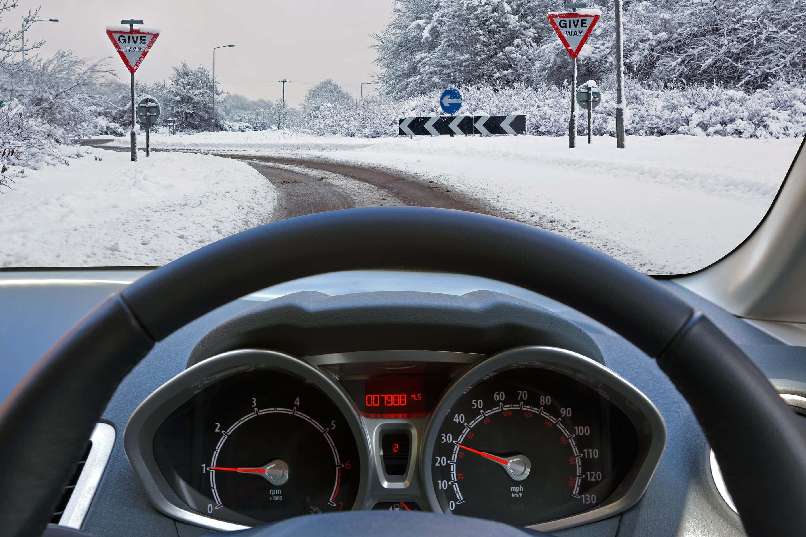 Winter Driving 桌布 壁紙 — 從車內看到前方積雪的道路，前景是儀表板和方向盤。