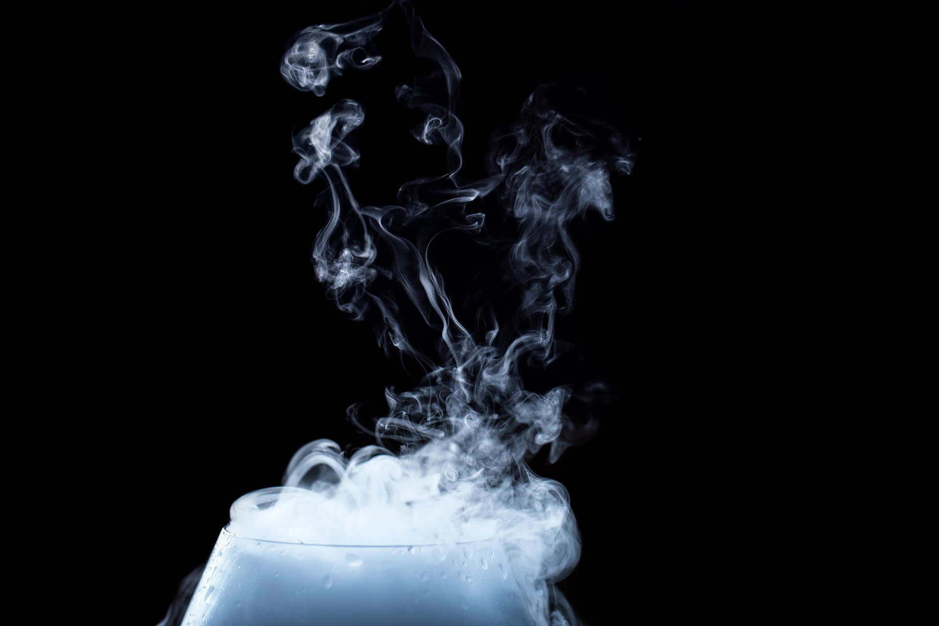 白色蒸氣從玻璃容器中升起，背景為黑色。