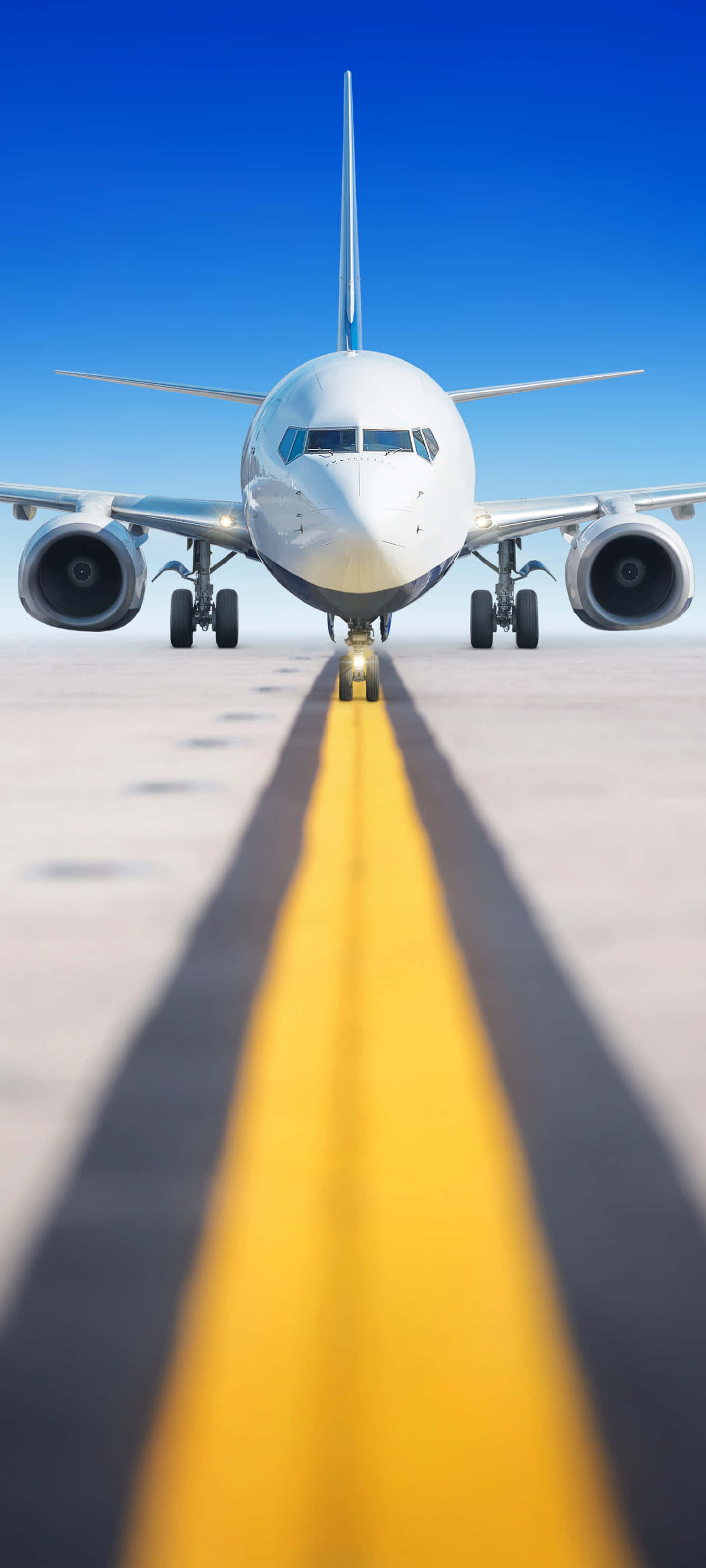 從飛機窗戶欣賞世界流動 壁紙 — 一架商用飛機在晴朗藍天下，面向跑道上一條醒目的黃色中心線。