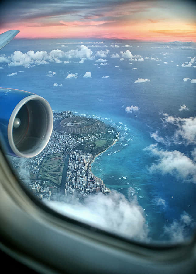 從飛機窗戶欣賞日出 壁紙 — 從飛機窗戶俯瞰檀香山歐胡島，鑽石頭山在日落時分，下方是充滿活力的藍色海洋。