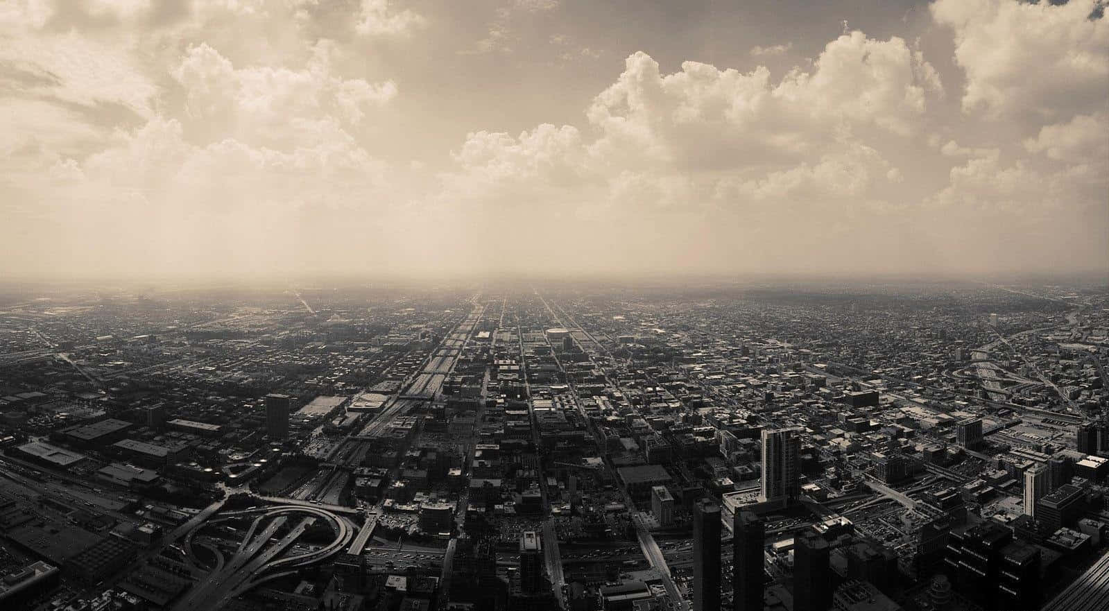 Sepia 桌布 壁紙 — 從高空俯瞰，在戲劇性的多雲天空下，以懷舊褐色調呈現的廣闊城市景觀。