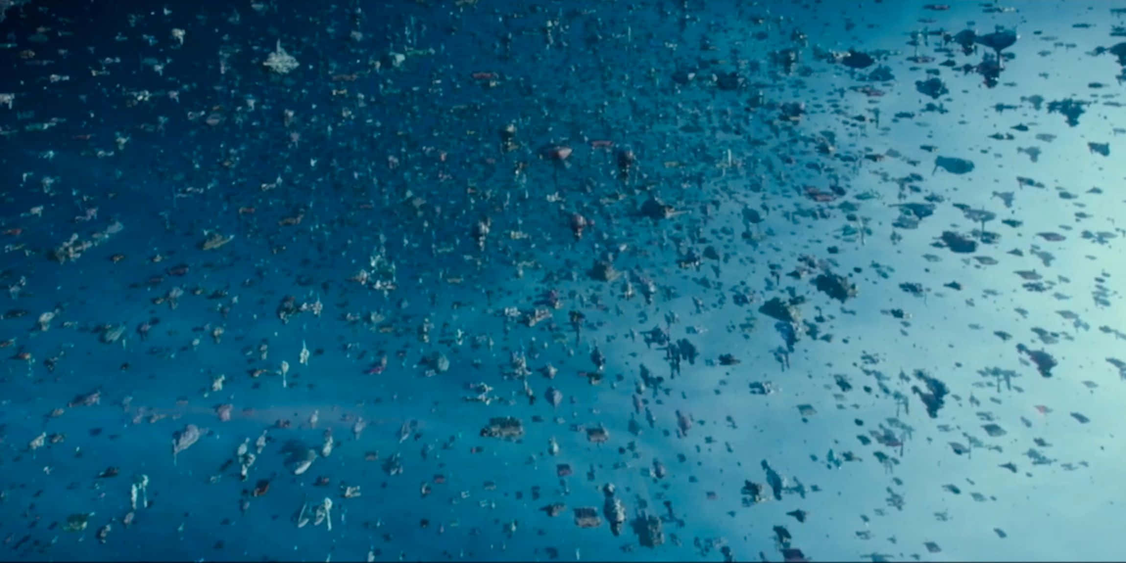 The Battle Of Exegol 桌布 壁紙 — 從高空俯瞰，無數深色漂浮碎片散落在廣闊的藍色海洋表面。