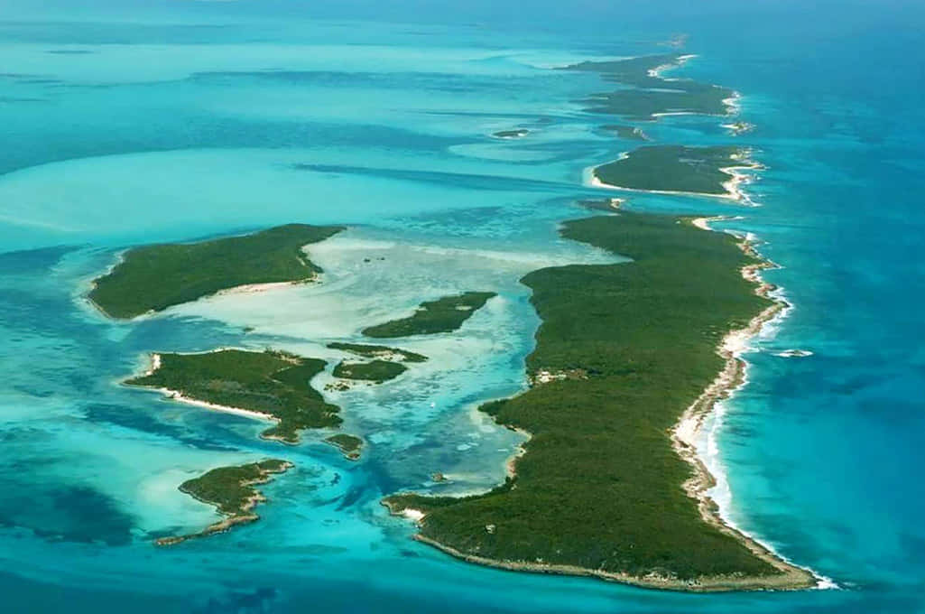 Bahamas Island 桌布 壁紙 — 從高空俯瞰一片翠綠的島鏈，周圍環繞著充滿活力的碧綠海水和淺水潟湖。