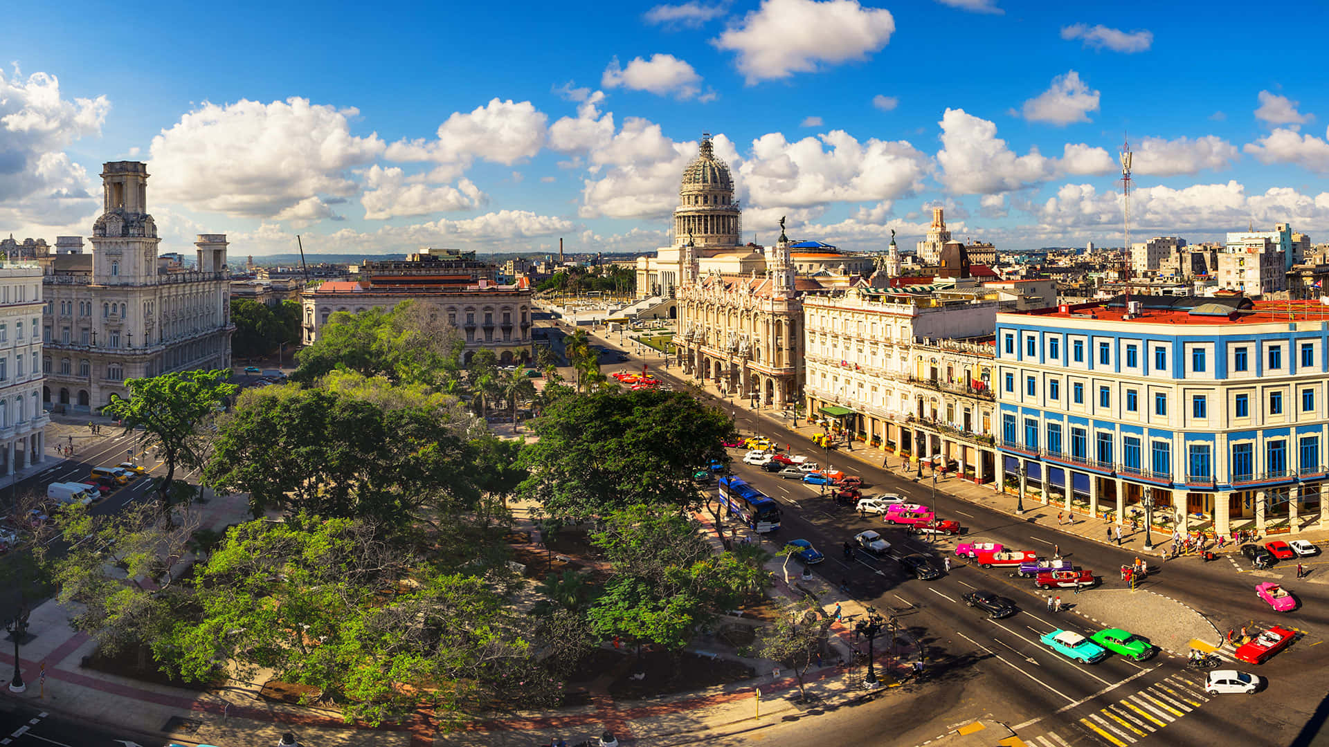 Cuba 桌布 壁紙 — 從高空俯瞰夏灣拿充滿活力的街道，兩旁是殖民時期建築和色彩繽紛的經典汽車，在晴朗的藍天和白雲下。