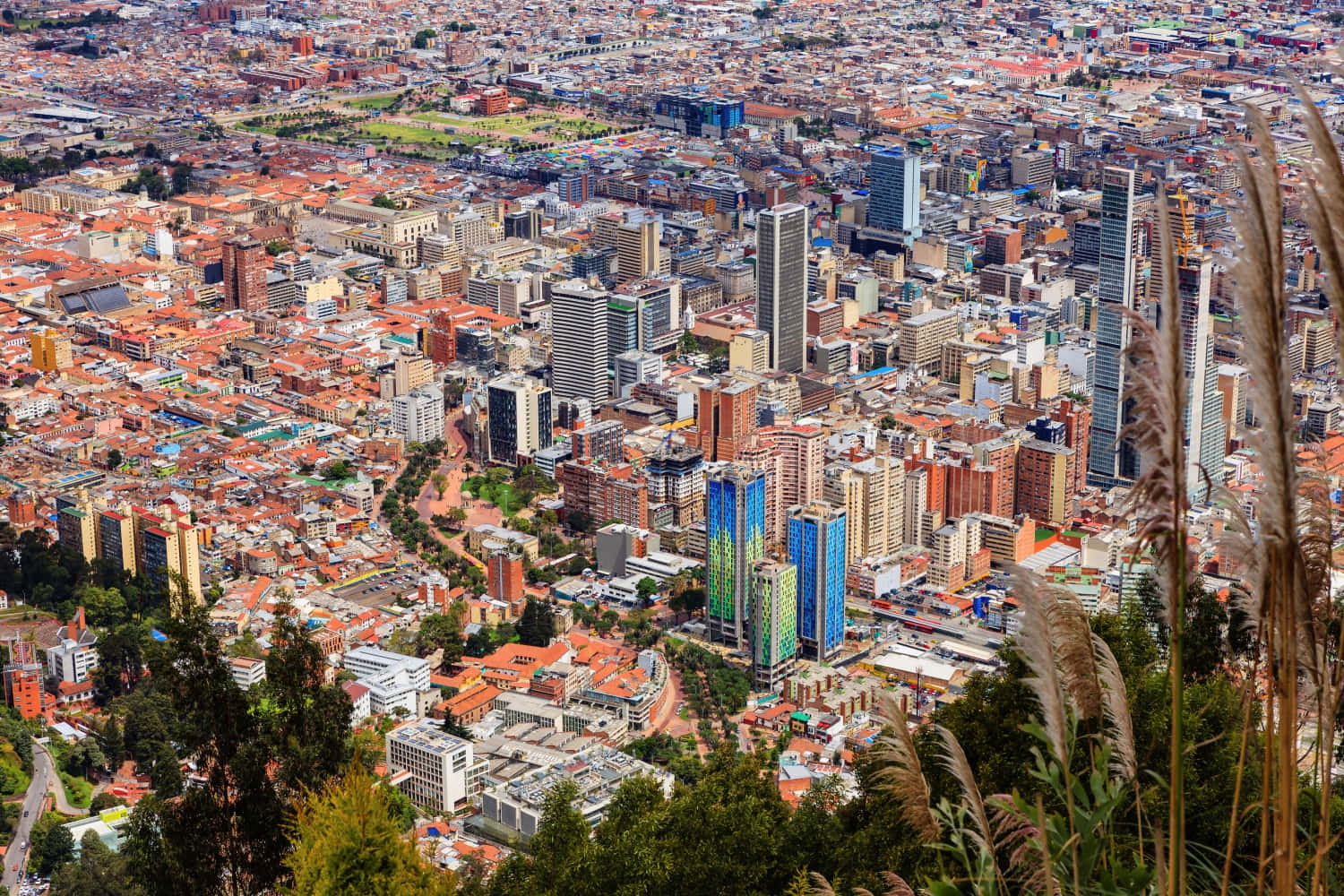 Colombia 桌布 壁紙 — 從高空俯瞰廣闊的城市景觀，密集的住宅區和現代摩天大樓在明亮的日光下。