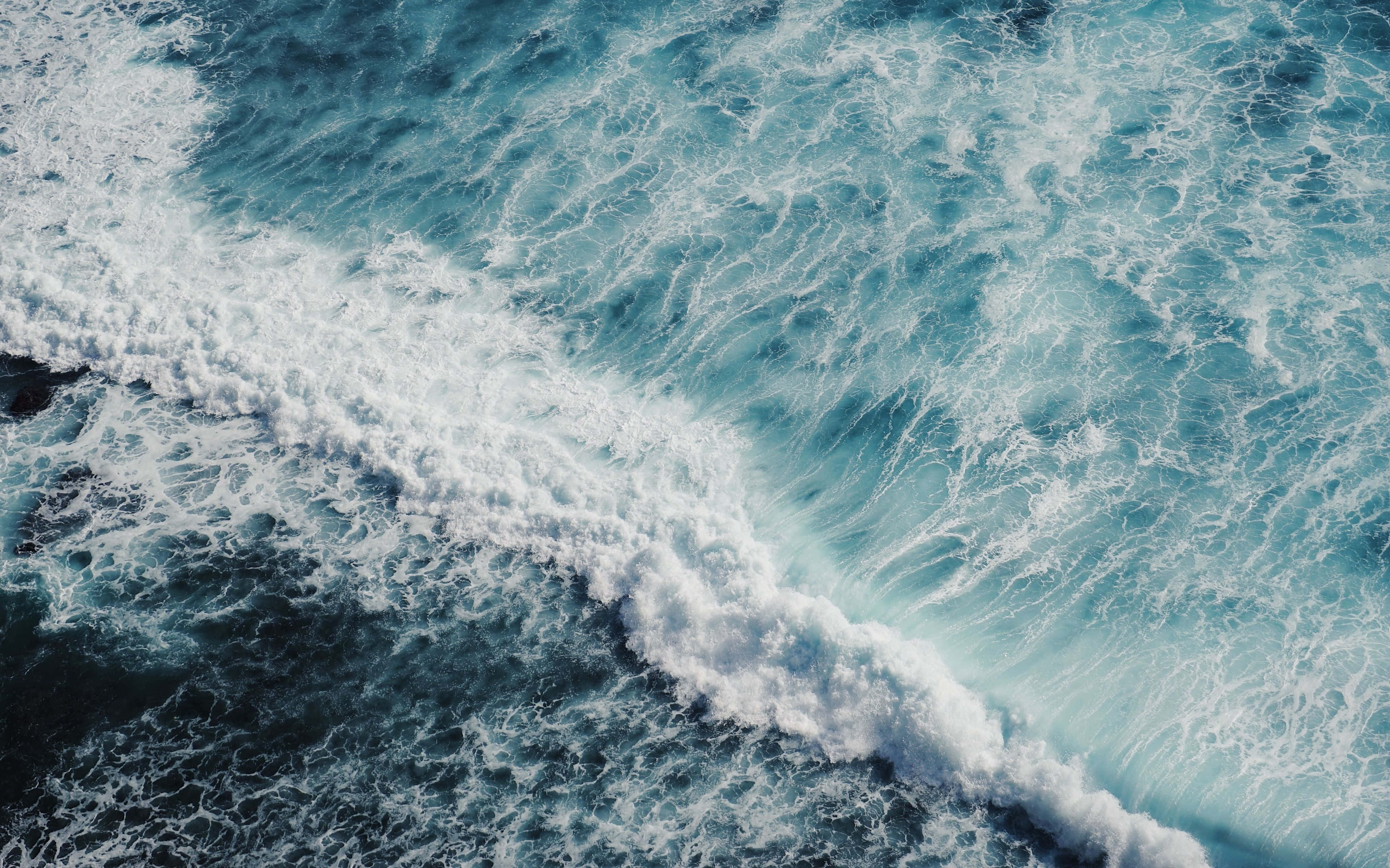 waves 桌布 壁紙 — 從高空俯瞰洶湧的海浪拍打深藍色海水，激起白色泡沫。