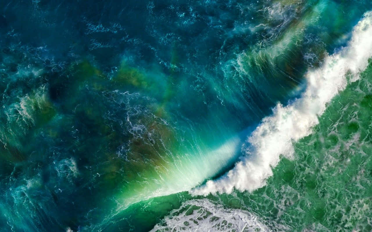 海浪 桌布 壁紙 — 從高空俯瞰洶湧的海浪拍打著白色泡沫，撞擊在充滿活力的藍綠色和綠色海面上。