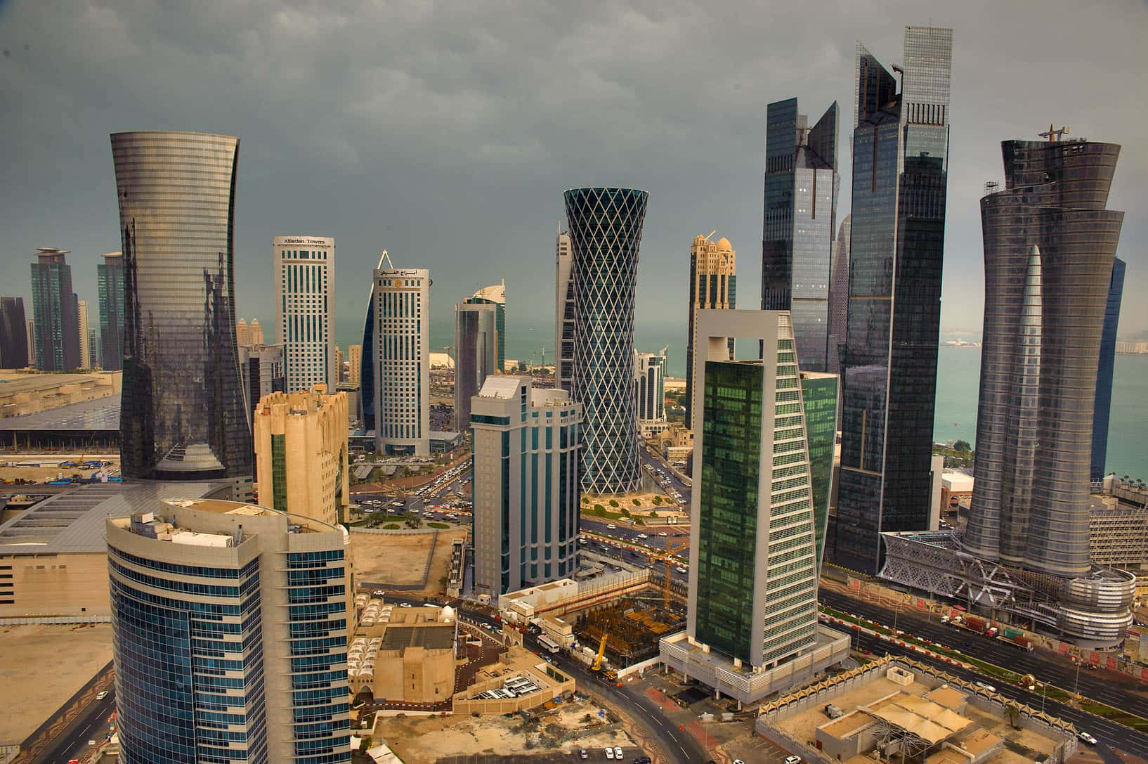 Qatar 桌布 壁紙 — 從高空俯瞰現代摩天大樓，其反射玻璃幕牆在陰天之下，眺望沿海城市景觀。