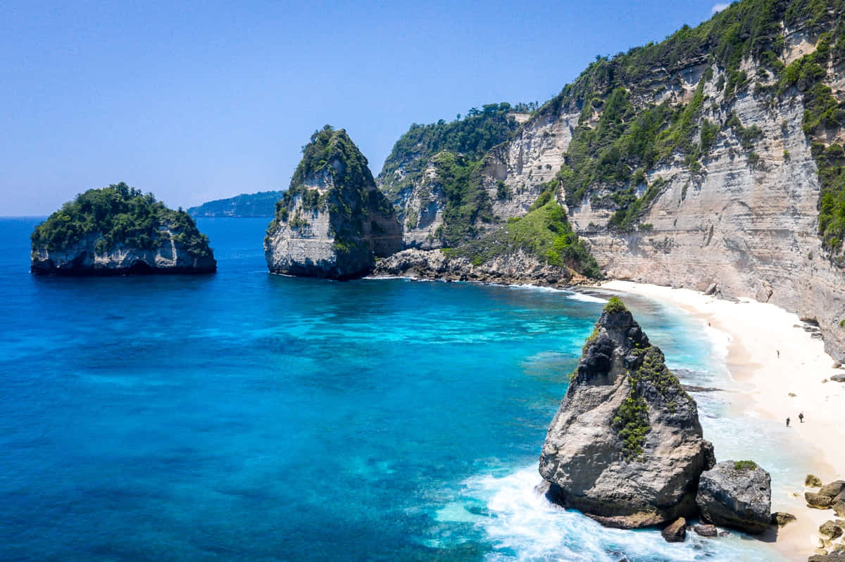 Bali Island 桌布 壁紙 — 從高空俯瞰的熱帶海灣，擁有碧綠色的海水、白色沙崖和茂密的綠色植物，在明亮的藍天下。