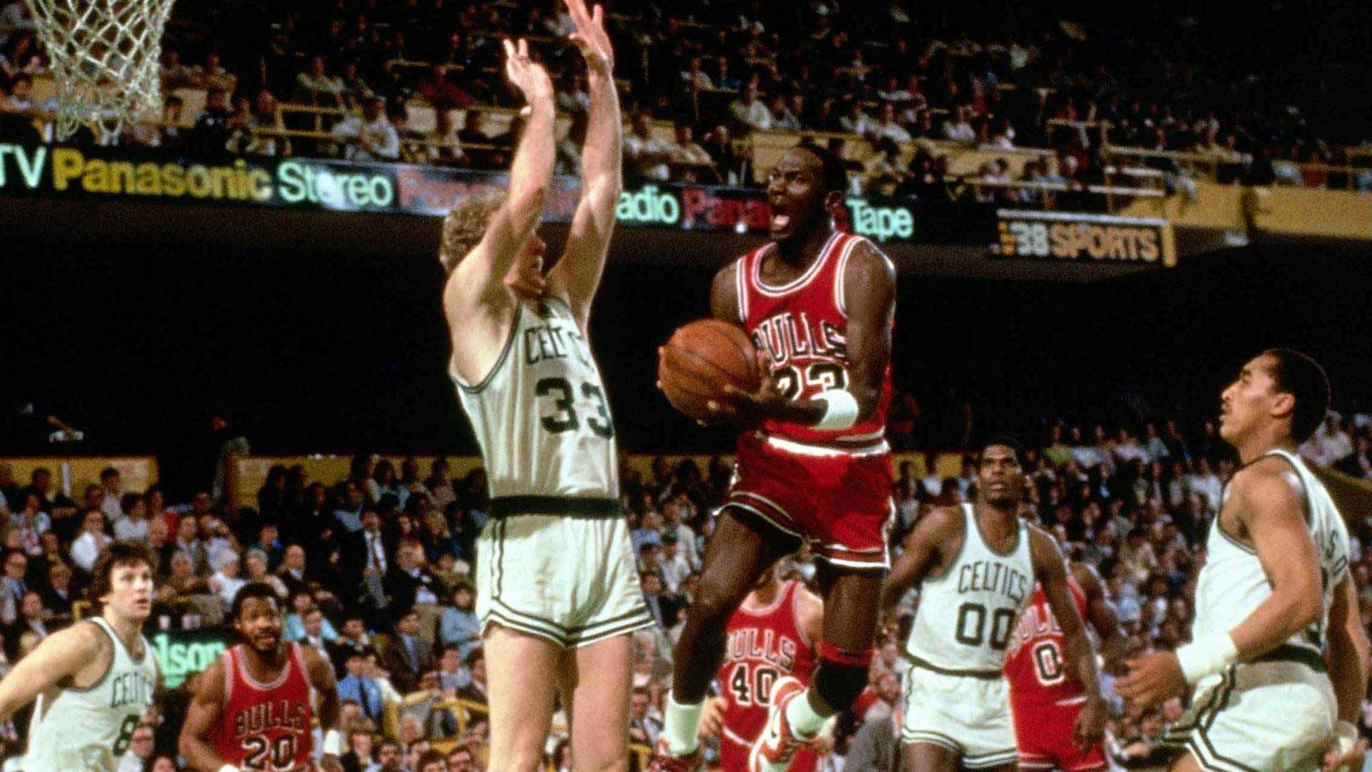復古NBA總決賽賽事 壁紙 — 米高佐敦身穿紅色公牛球衣跳起入樽，塞爾特人防守球員舉臂阻擋，場館座無虛席。