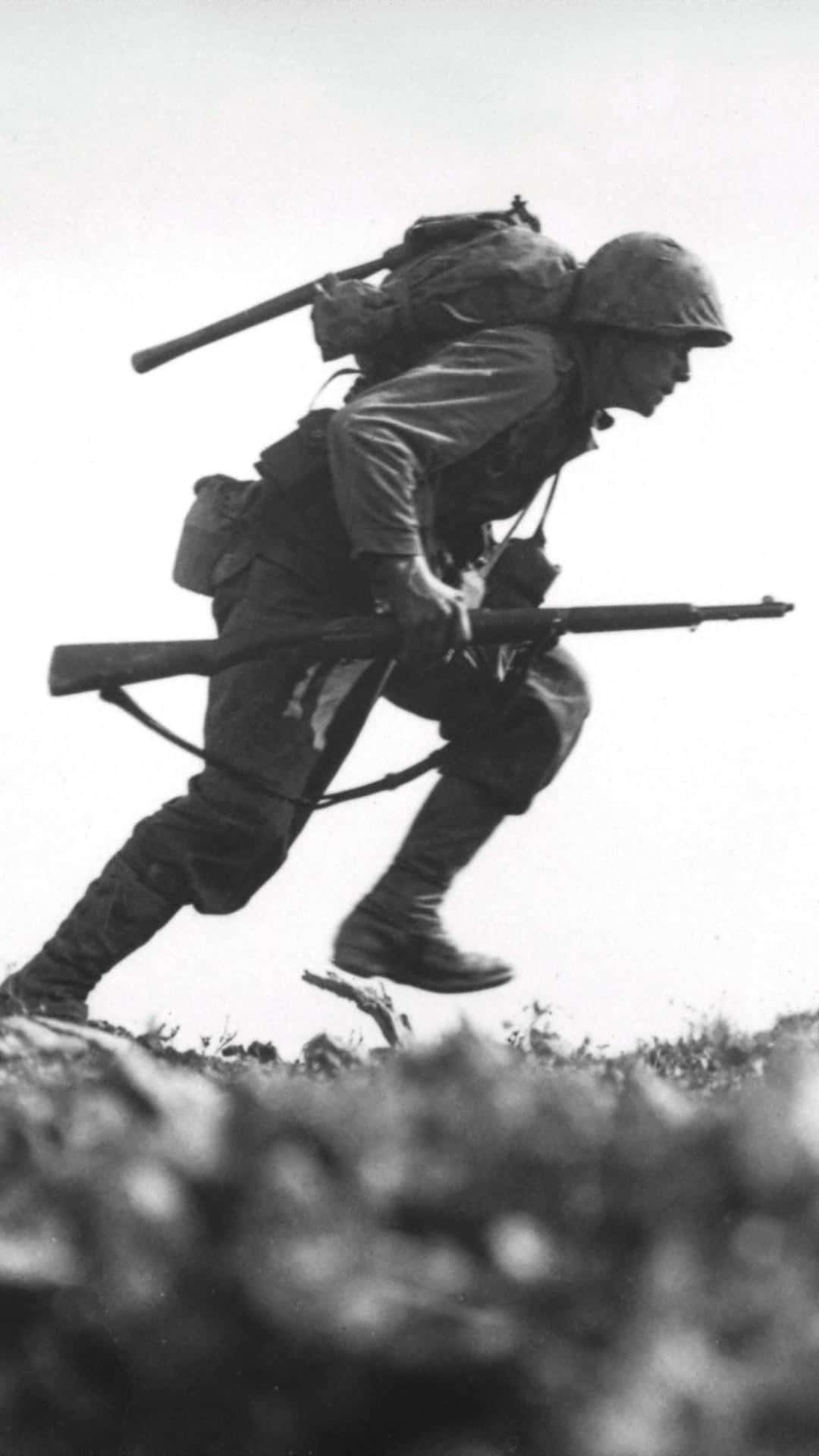 戰時黑白照片中，士兵手持步槍跑上山坡。