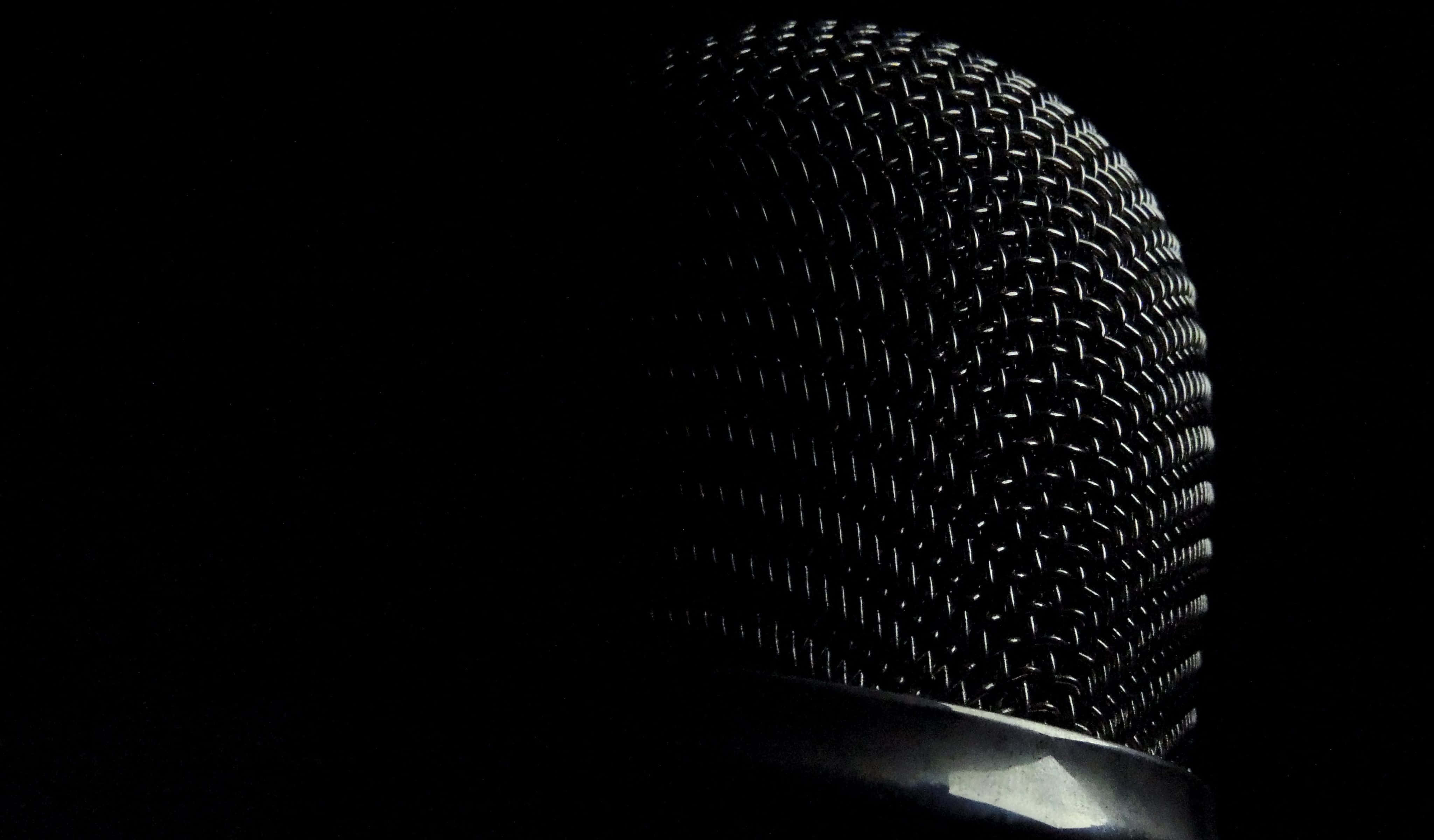 Microphone 桌布 壁紙 — 復古咪高峰金屬網格特寫，在漆黑背景下被照亮。