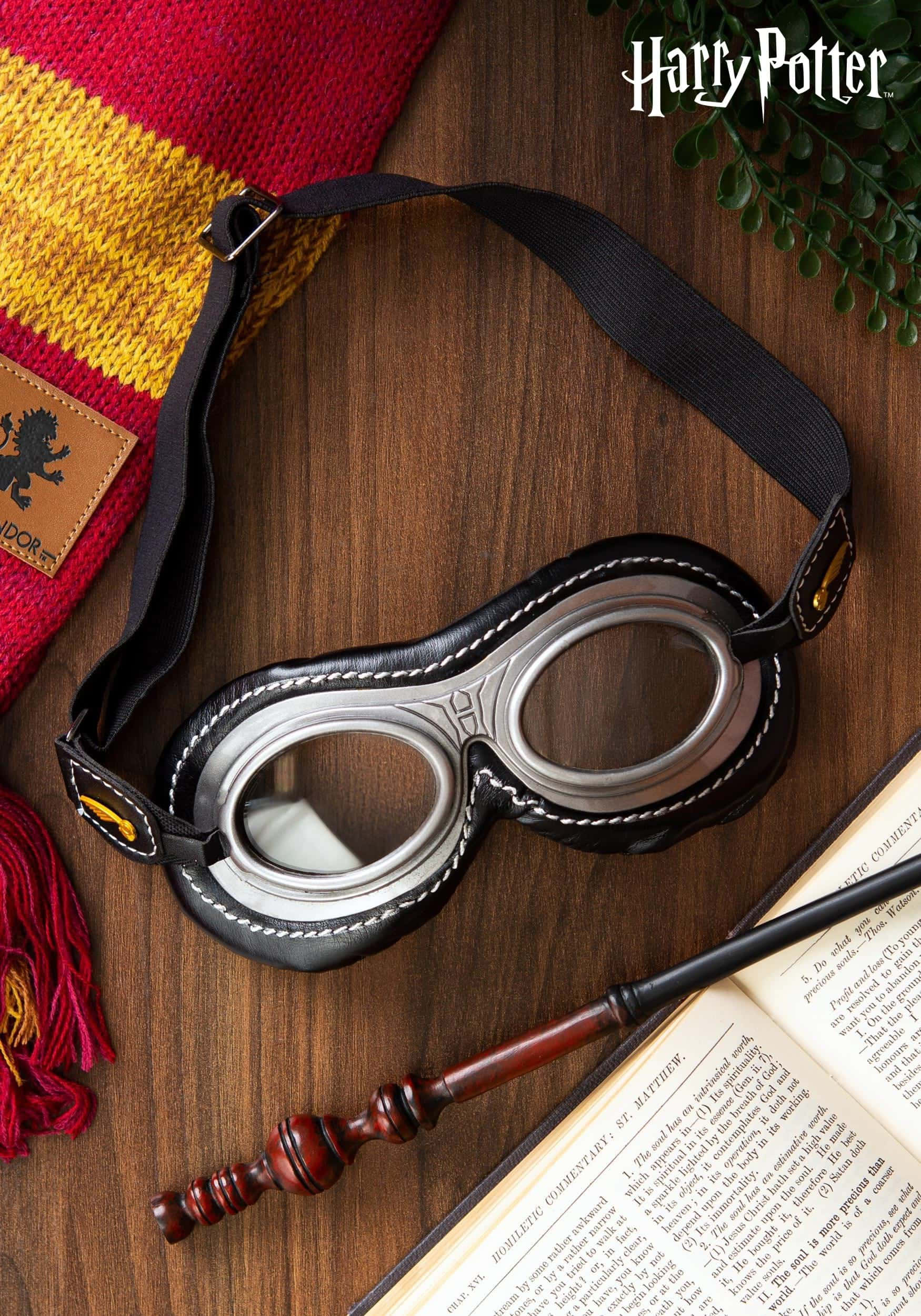 Quidditch 桌布 壁紙 — 復古哈利波特飛行護目鏡放在木桌上，旁邊有葛萊芬多圍巾、魔杖和打開的書。