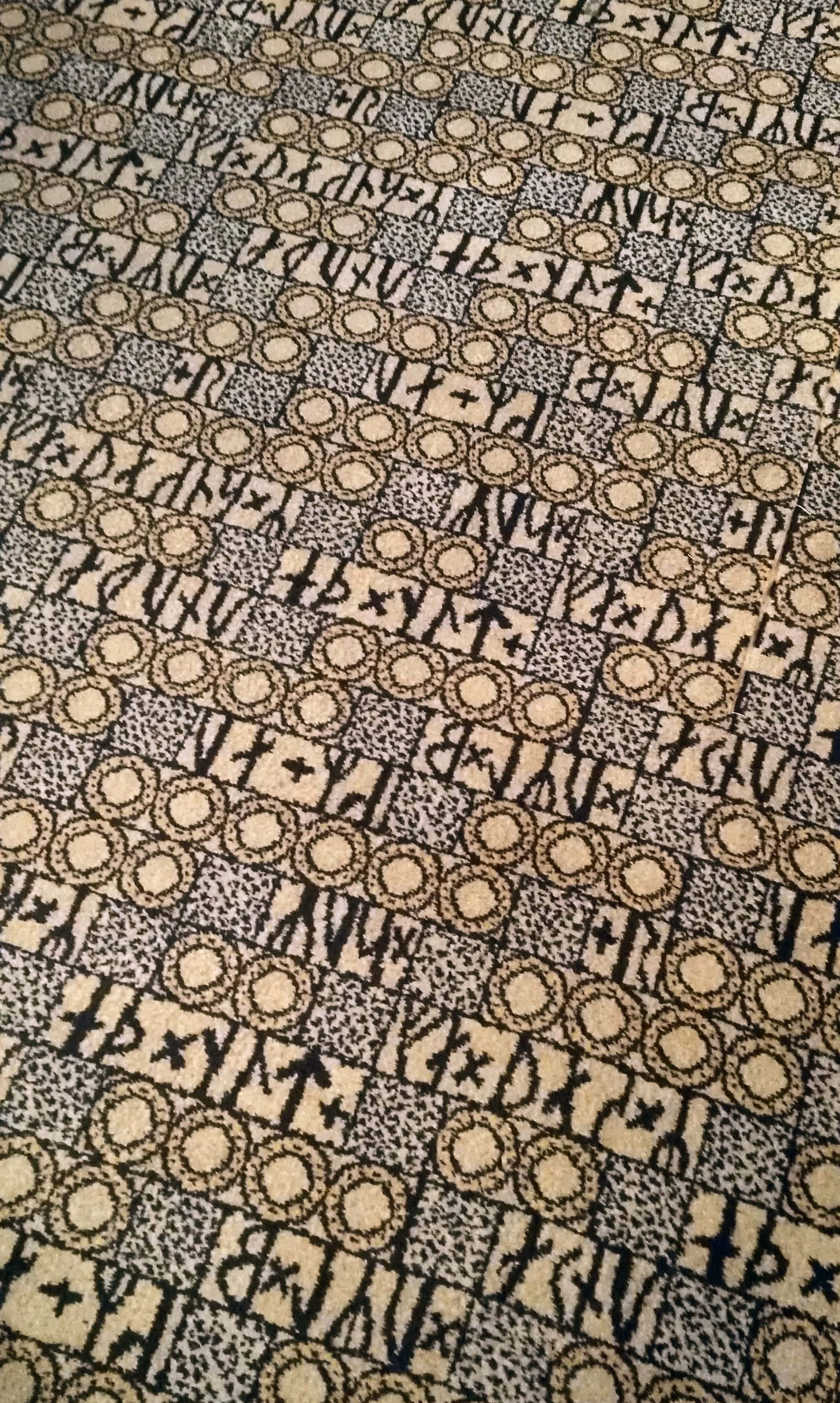 Carpet 桌布 壁紙 — 復古幾何圖案地毯的特寫，帶有重複的圓圈和抽象形狀，採用米色和深色調。