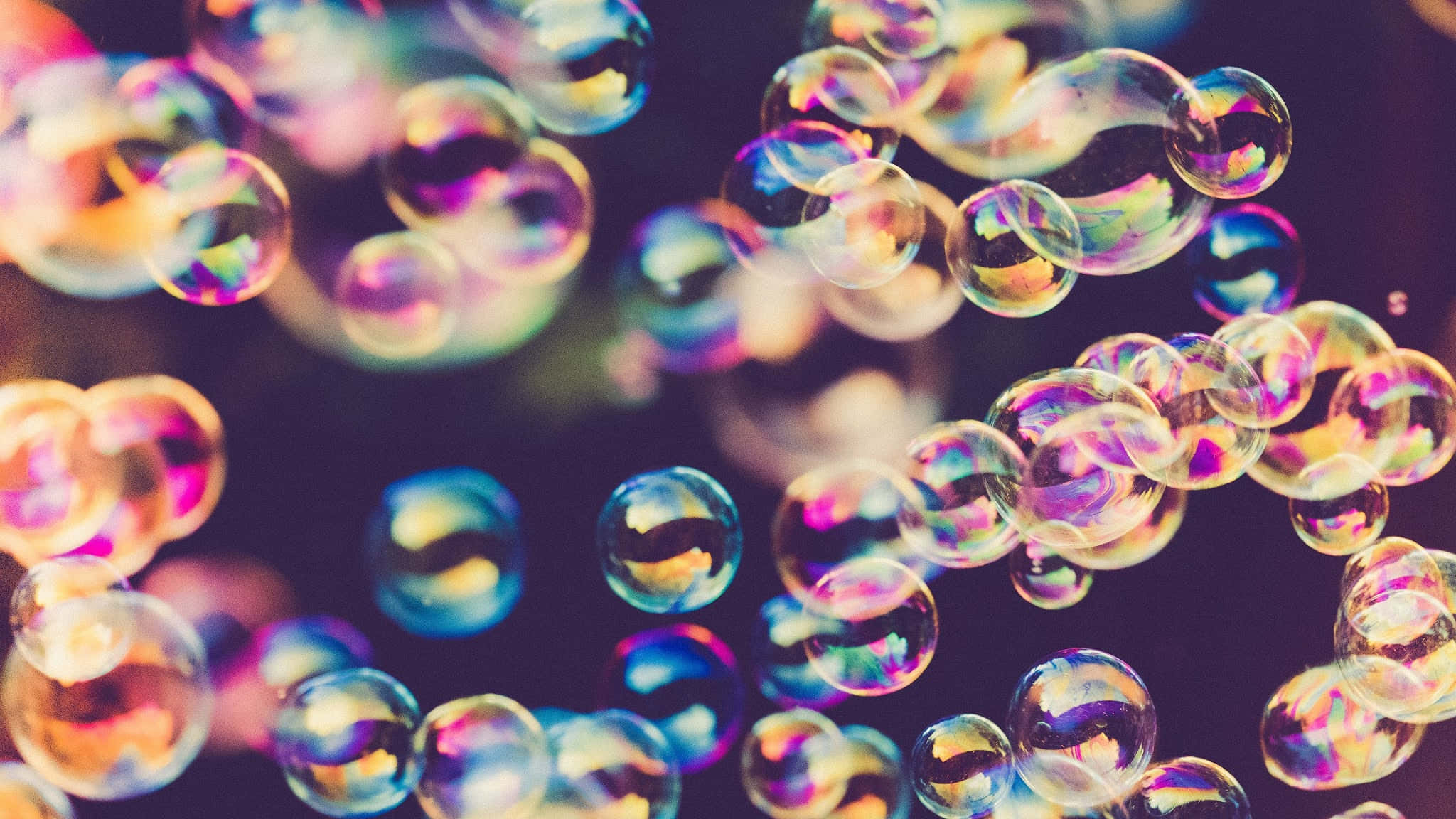 復古彩虹氣泡風景背景 壁紙 — 彩虹色的肥皂泡在黑暗模糊的背景上漂浮並閃爍著彩虹色調。