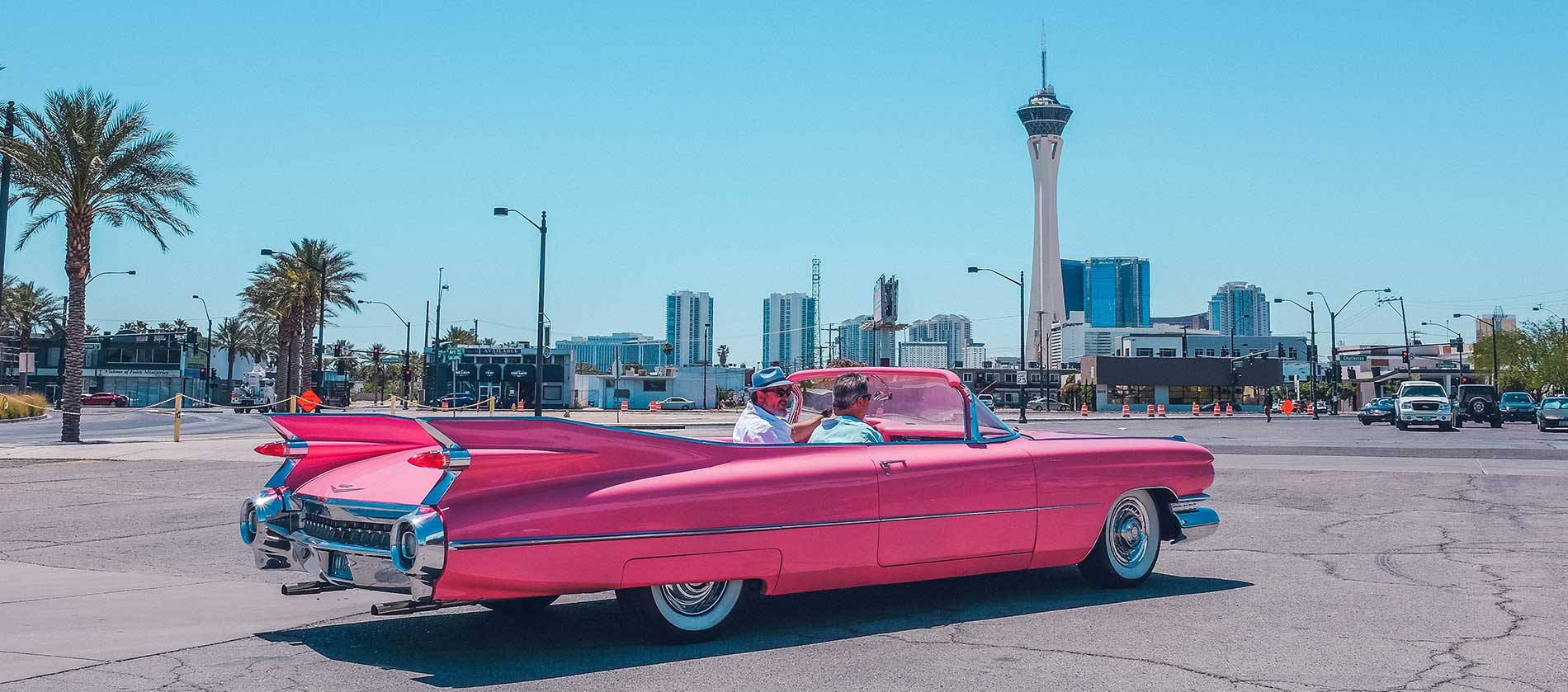 粉紅色復古敞篷車在拉斯維加斯行駛，背景是Stratosphere Tower。