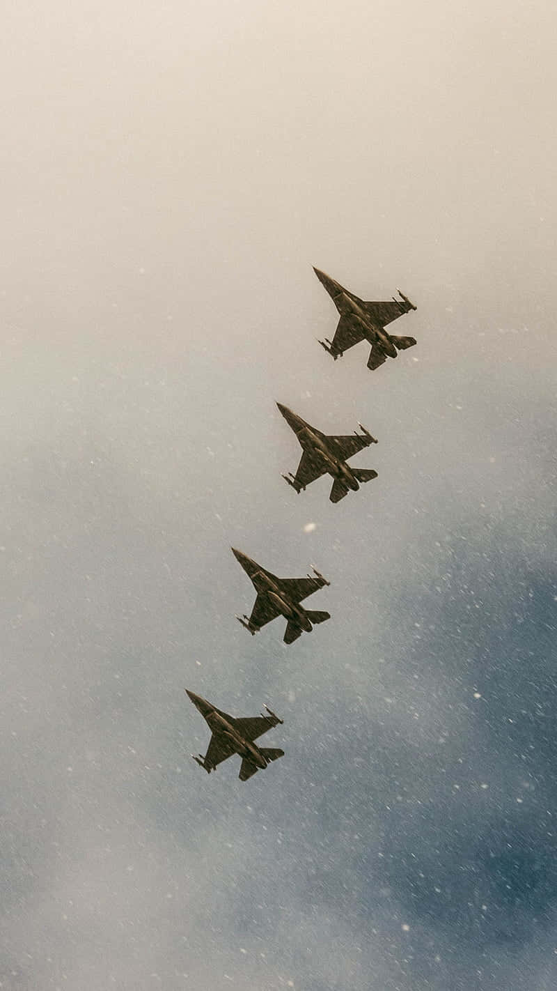 復古濾鏡的軍用飛機編隊安卓巨無霸背景 壁紙 — 四架戰鬥機以緊密編隊翱翔，背景是帶有柔和藍灰色調的多雲天空。