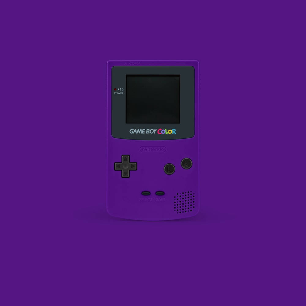 復古紫色Game Boy Color掌機 壁紙 — 一部充滿活力的紫色 Game Boy Color 主機，置中於純紫色背景上，帶有柔和陰影。