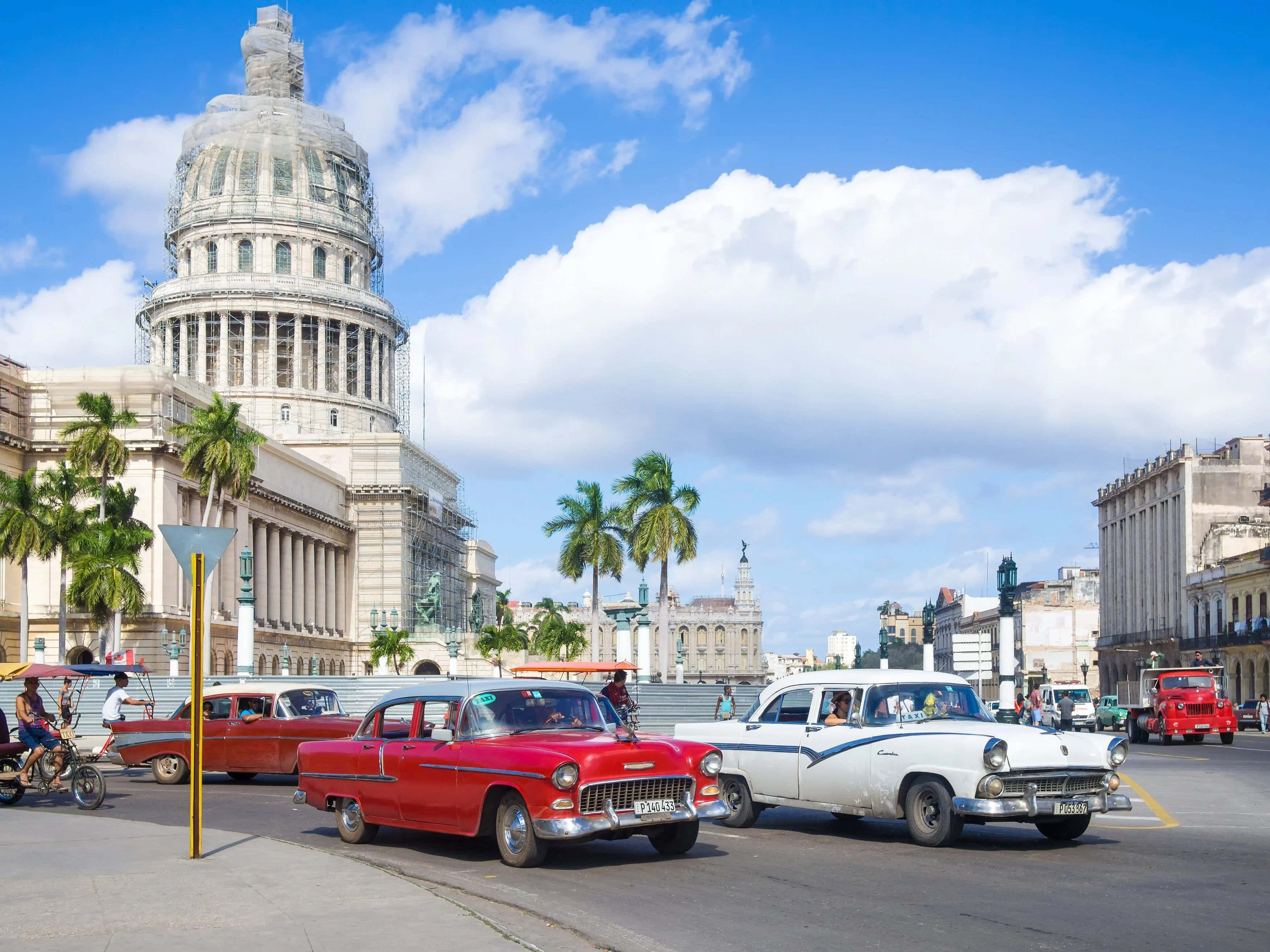 Cuba 桌布 壁紙 — 復古美國汽車在哈瓦那的國會大廈前駛過，天空湛藍，點綴著蓬鬆的白雲。