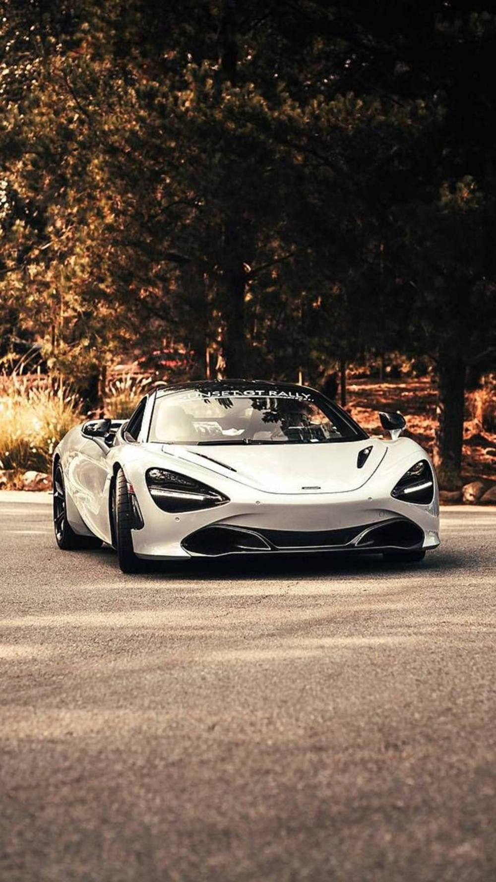 日落時分，白色McLaren跑車停泊在森林道路上。