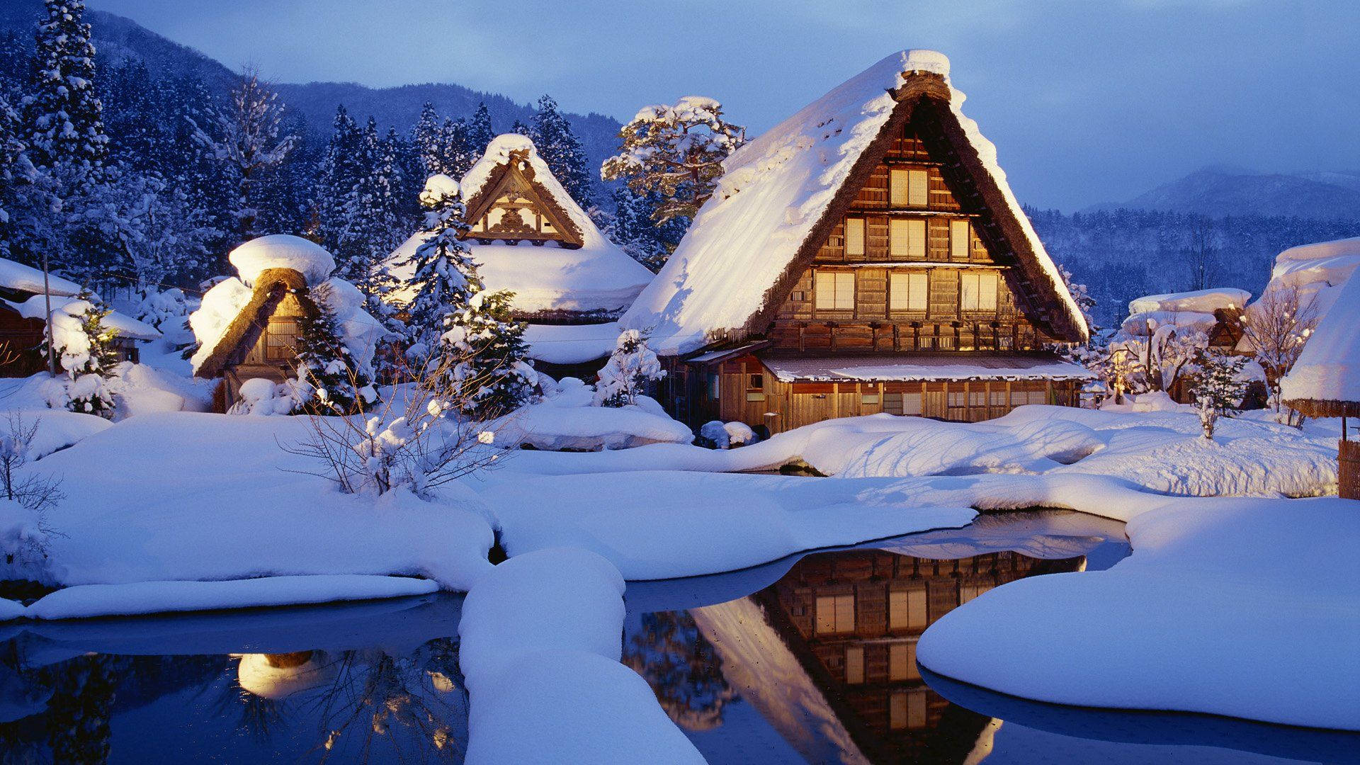 積雪的傳統日本房屋，溫暖的燈光在黃昏時分映照在結冰的溪流中。