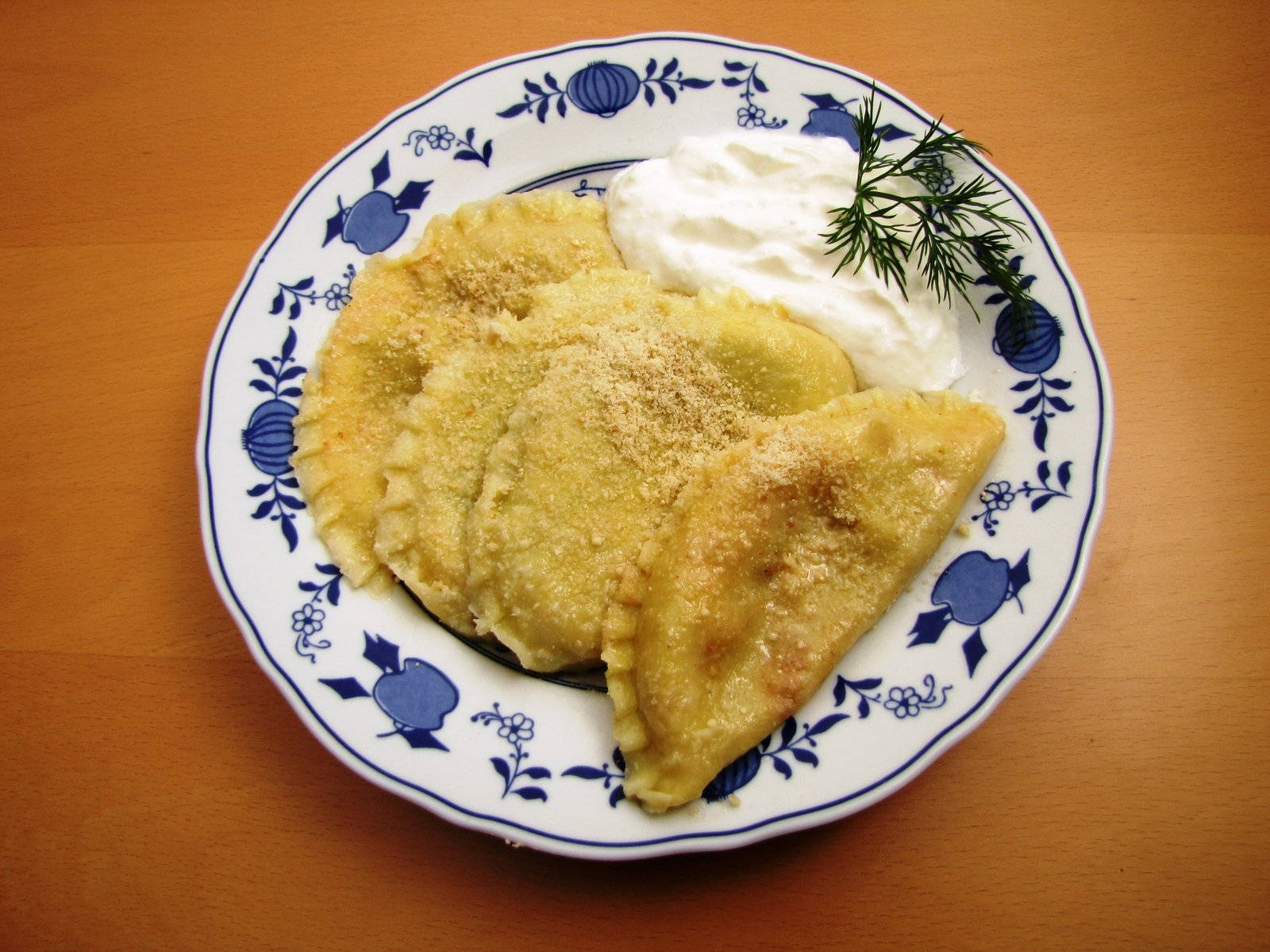 復古藍盤波蘭餃子 壁紙 — 金黃色炸波蘭餃子撒上麵包糠，配上酸忌廉和蒔蘿，放在藍色花卉圖案碟上。
