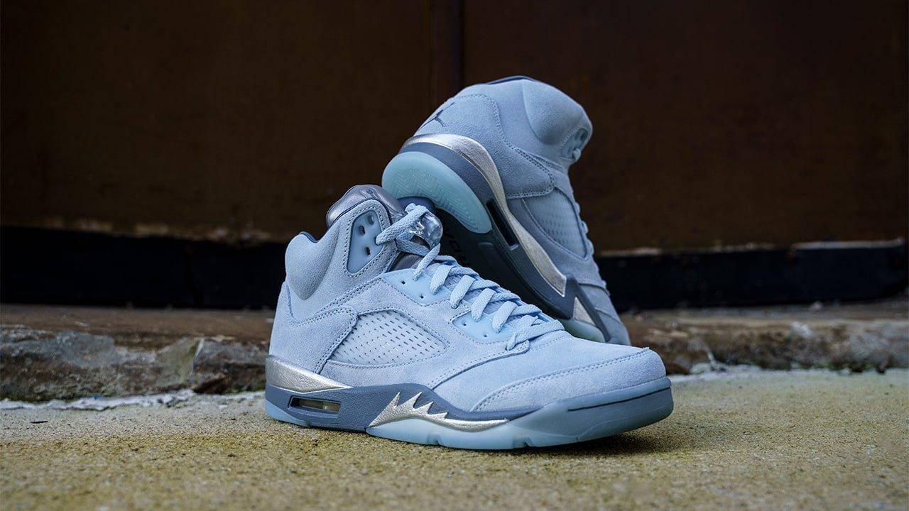 淺藍色麂皮 Air Jordan 5 運動鞋，帶有銀色點綴，放在混凝土階梯上。