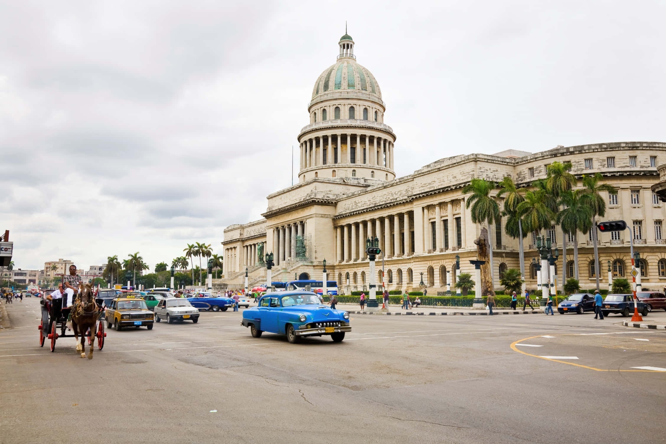 Cuba 桌布 壁紙 — 復古藍色汽車和馬車在陰天背景下，於宏偉的國會大廈前的繁忙街道上行駛。