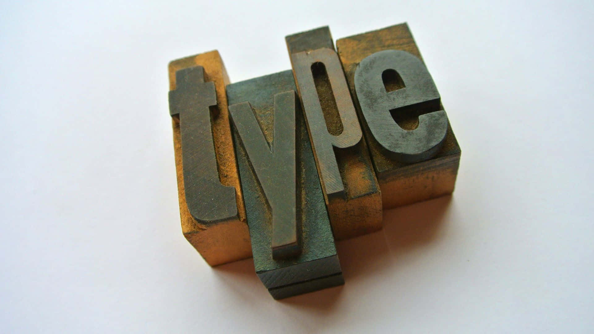 Typography 桌布 壁紙 — 復古金屬活字塊拼出「type」，對角排列在純白表面上。