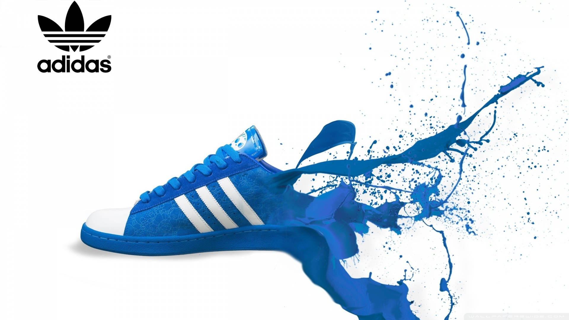 白色背景上帶有顏料飛濺效果的藍色 Adidas 運動鞋。
