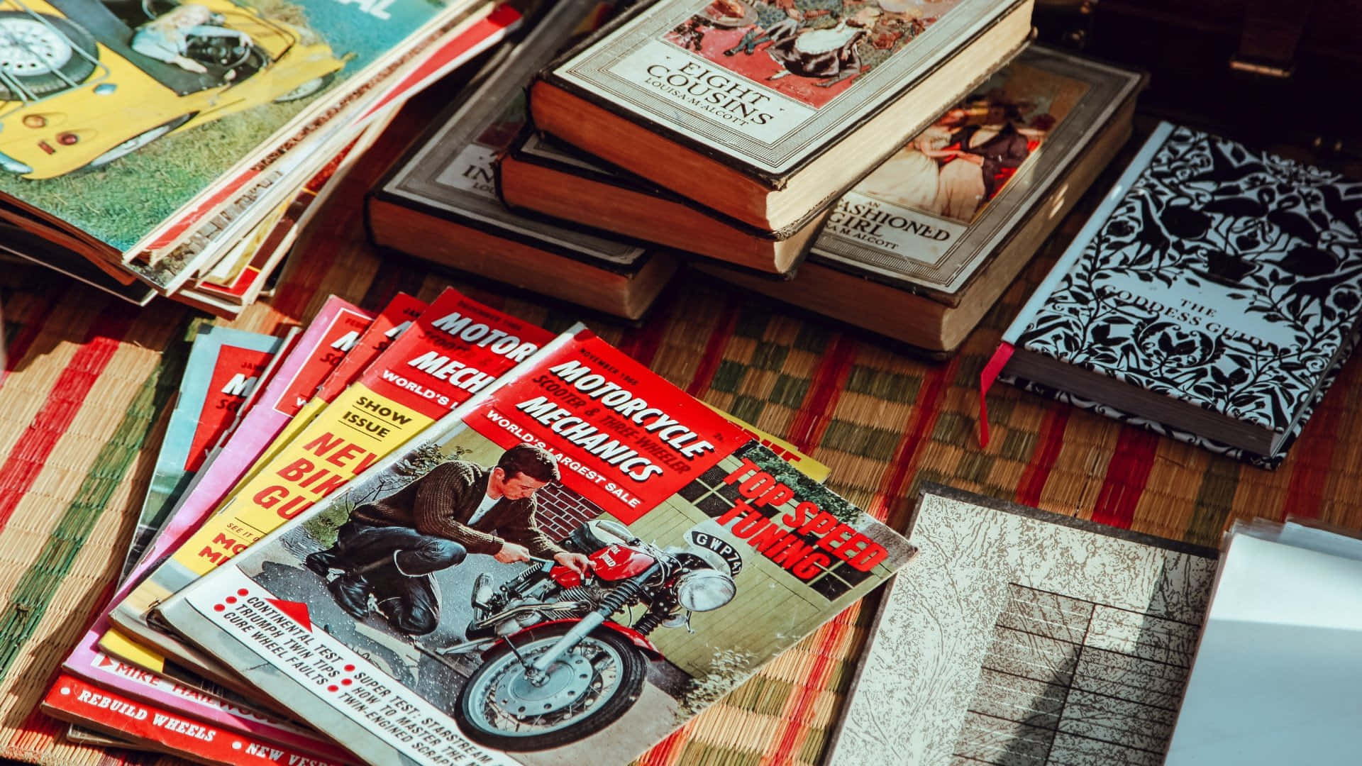 Beautiful Retro 桌布 壁紙 — 復古電單車雜誌和經典書籍放在一張條紋木桌上，沐浴在溫暖的陽光中。