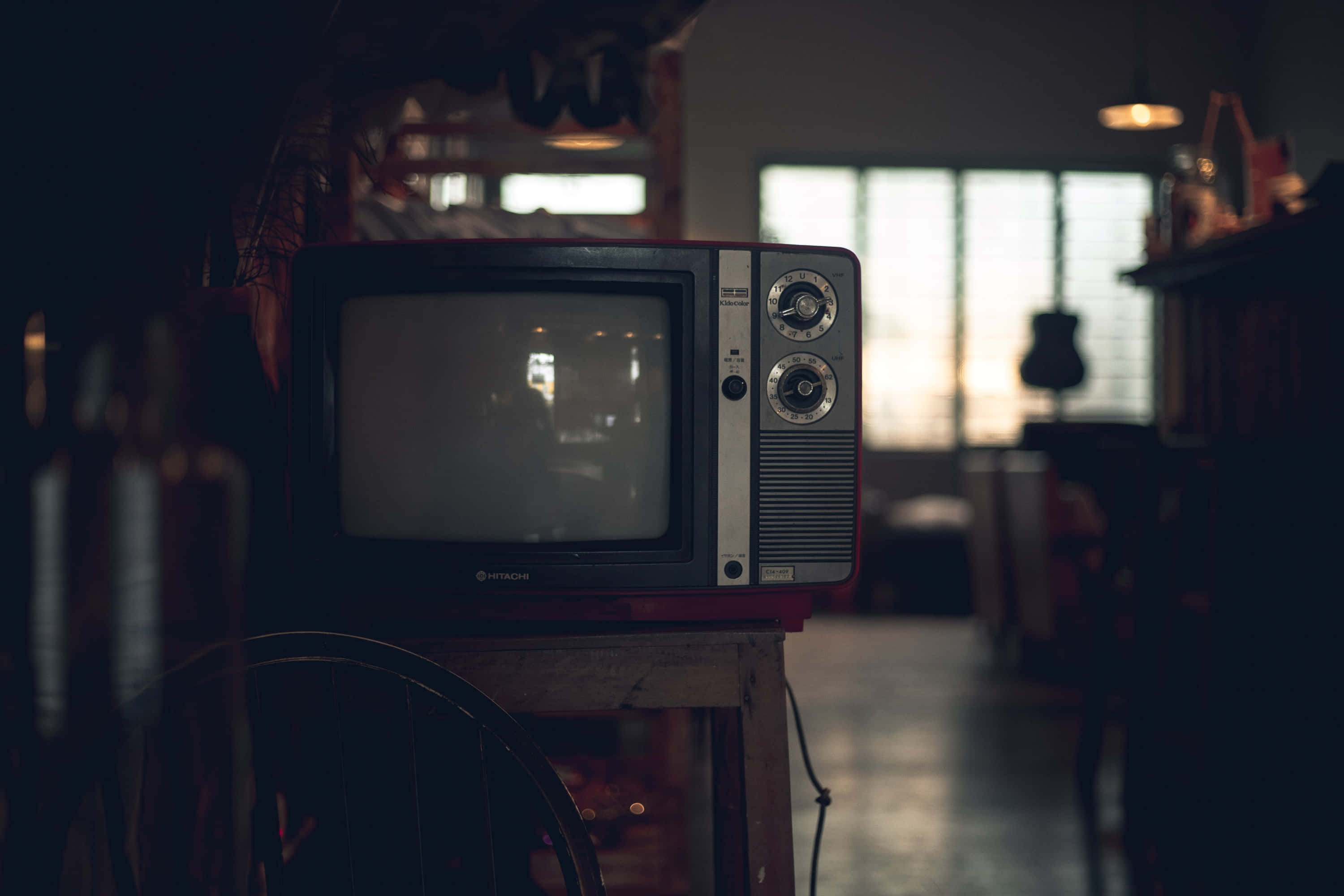 tv 桌布 壁紙 — 復古電視機放在木桌上，房間光線昏暗，柔和光線透過百葉簾照射進來。