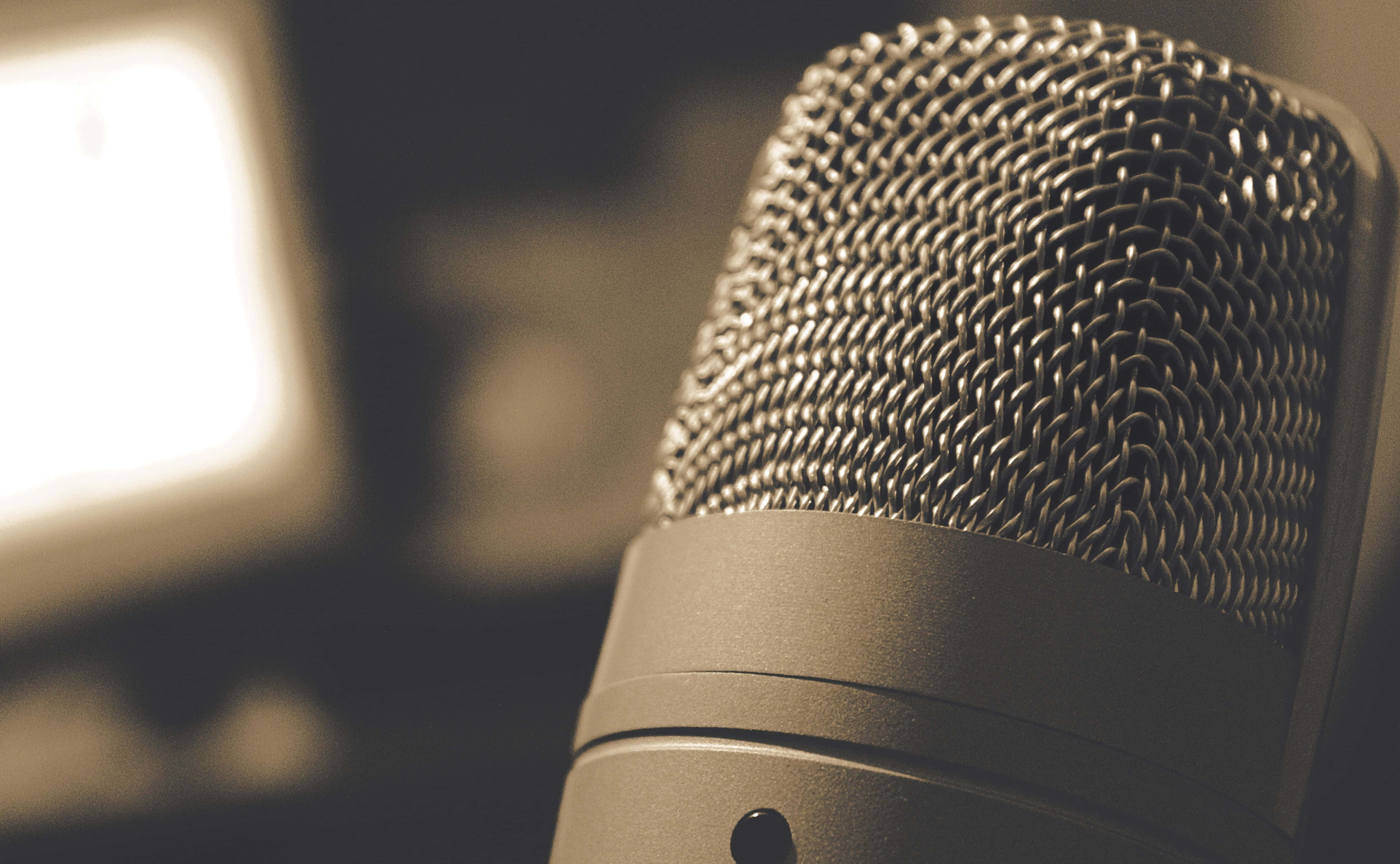 Microphone 桌布 壁紙 — 復古風格咪高峰的特寫，金屬網格柵浸浴在溫暖的懷舊色燈光中。