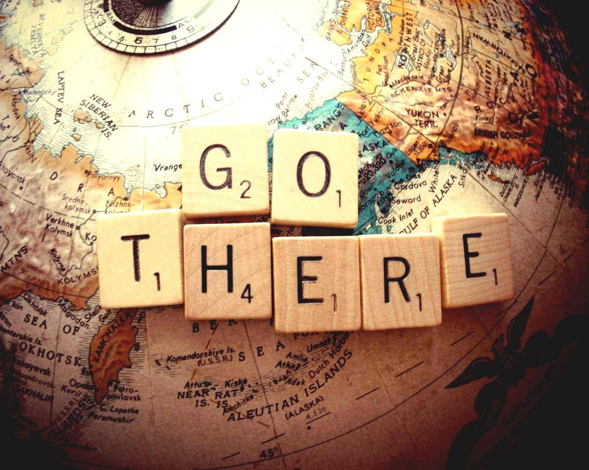 拼字磚在復古地球儀上拼出 GO THERE。