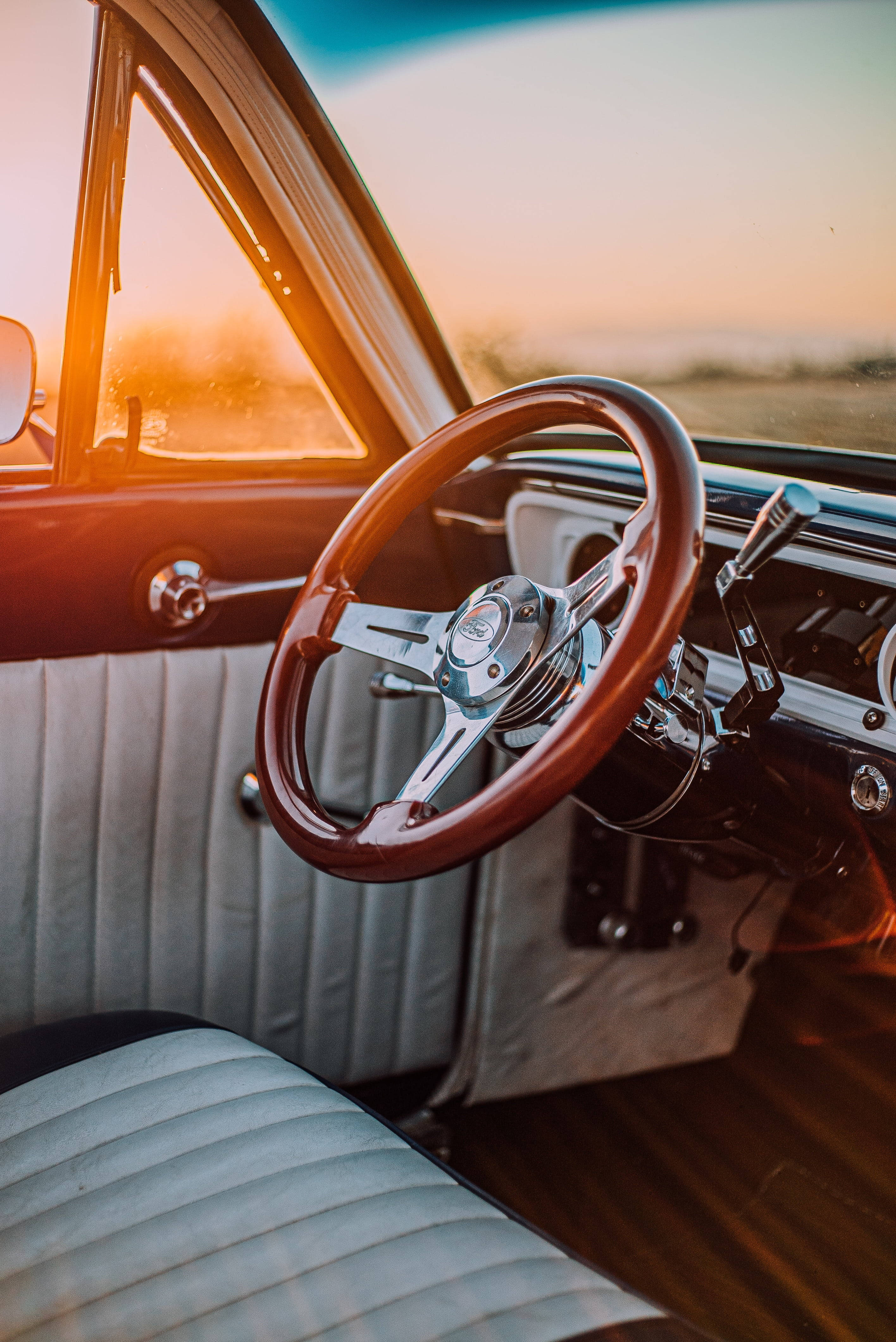 復古風格的方向盤 壁紙 — 夕陽的餘暉將復古車的木質方向盤和鍍鉻儀表板沐浴在溫暖的琥珀色光中。