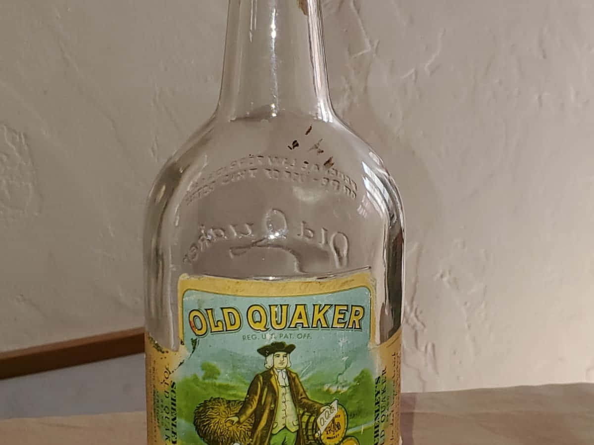 復古風格的舊瓶 壁紙 — 復古Old Quaker威士忌酒瓶，帶有浮雕玻璃和彩色標籤，上面有一個拿著玉米的殖民時期男子。