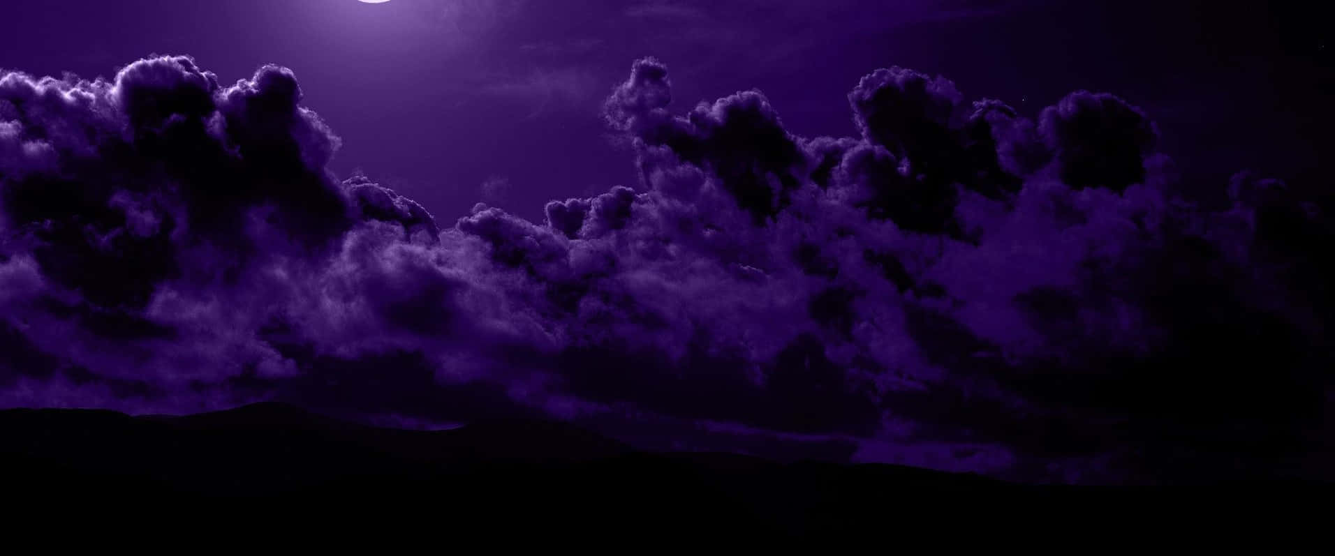紫色夜空，月光下的雲朵和黑暗的山丘輪廓