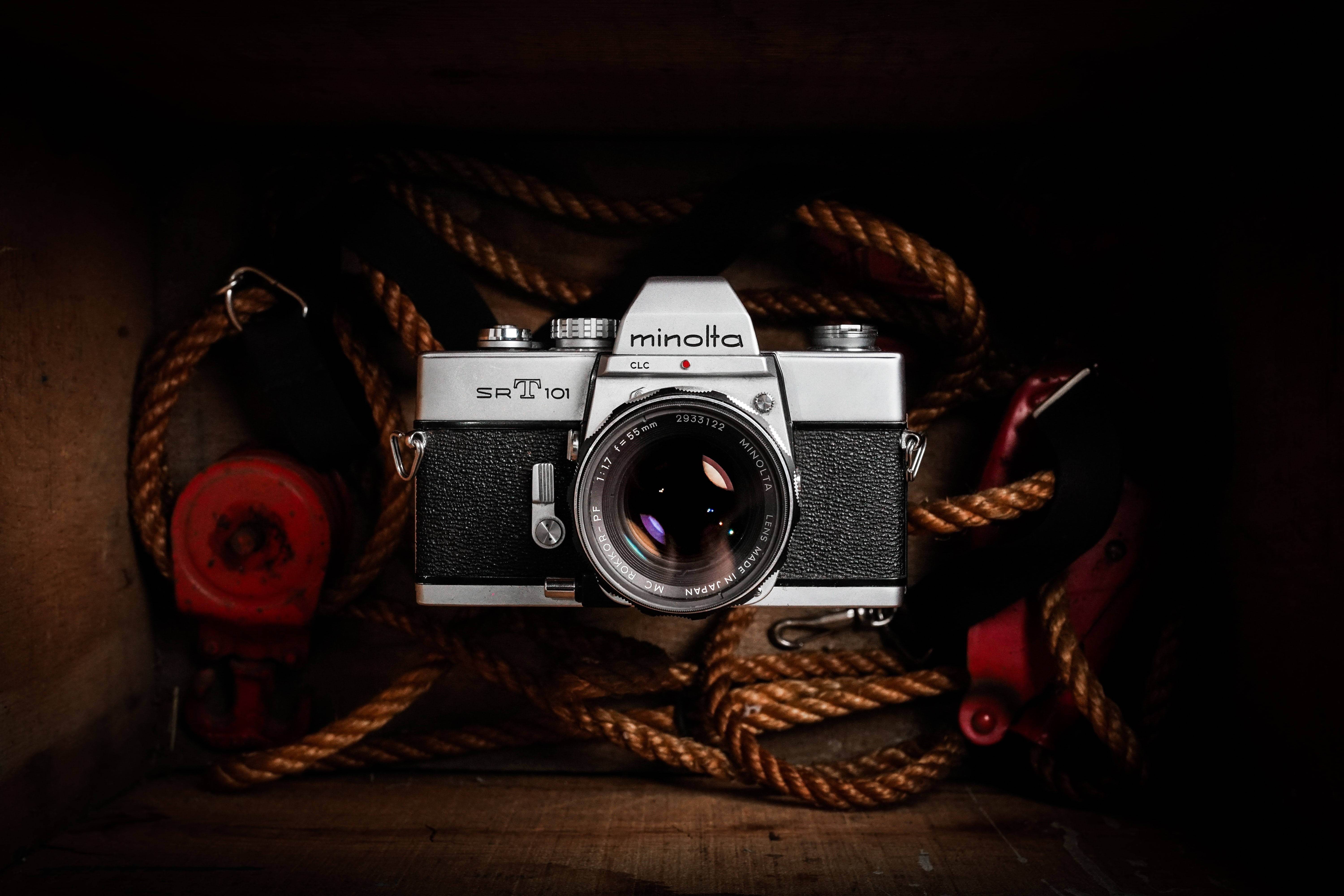 復古風格美能達相機 壁紙 — 一部復古銀色Minolta SR-T 101相機安放在一個昏暗的木箱中，周圍是粗大的棕色繩索和紅色航海裝備。