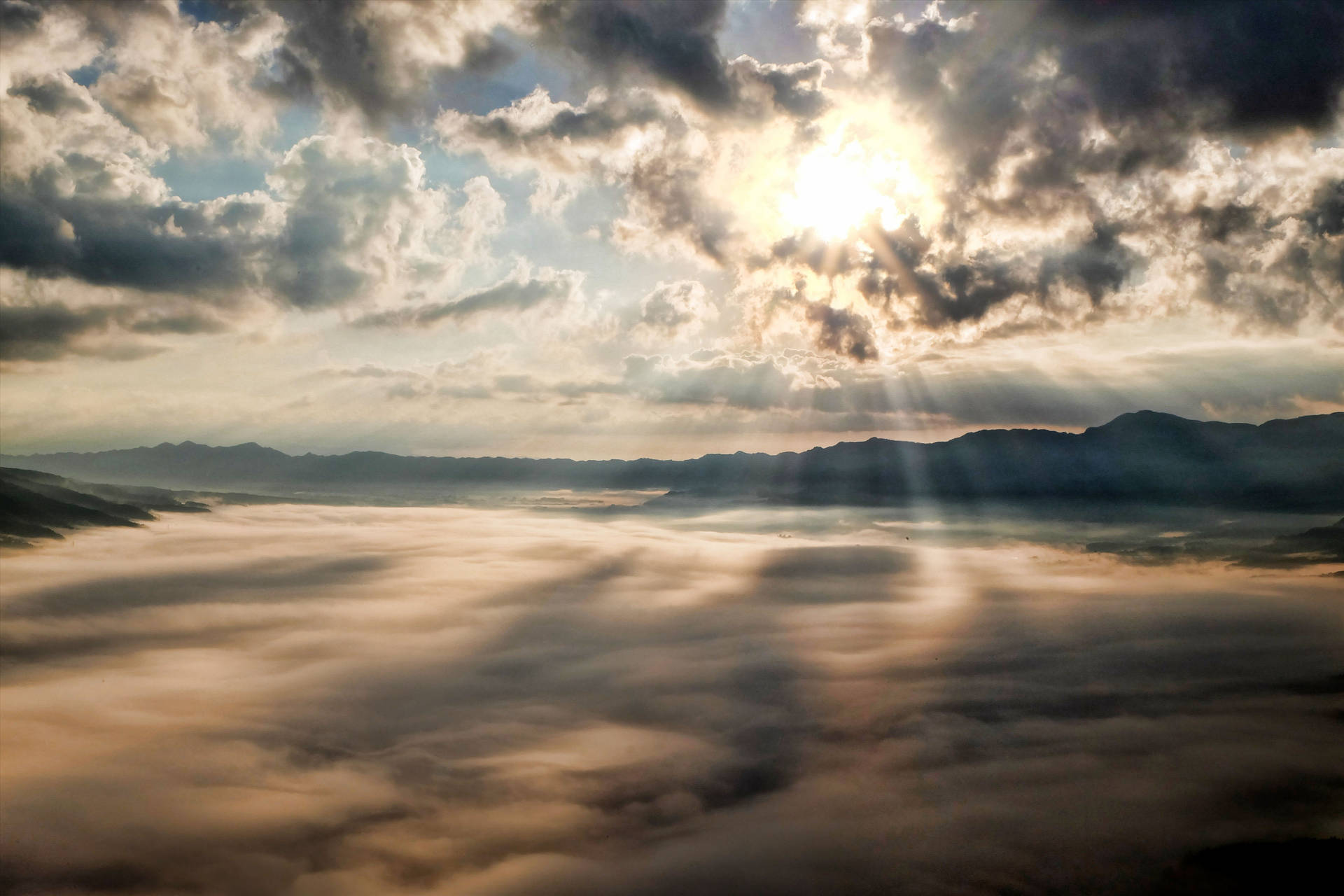 陽光穿過雲層，照耀在霧氣瀰漫的山谷和遠山之上。