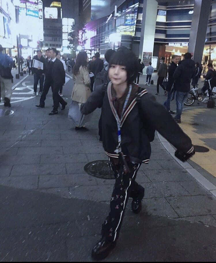 年輕人穿著水手服裝，戴著兔耳朵，在夜晚繁忙的城市街道上擺姿勢。