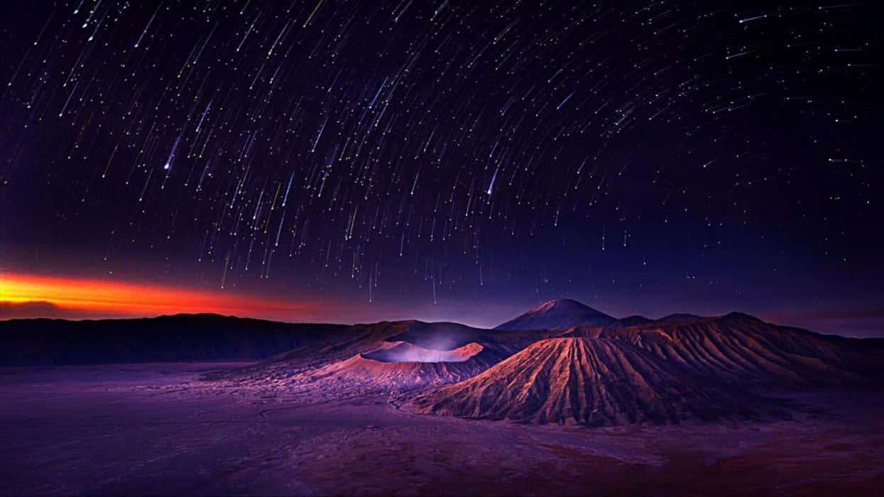 在充滿活力的橙色和紫色色調的星空暮色天空下的火山群山。