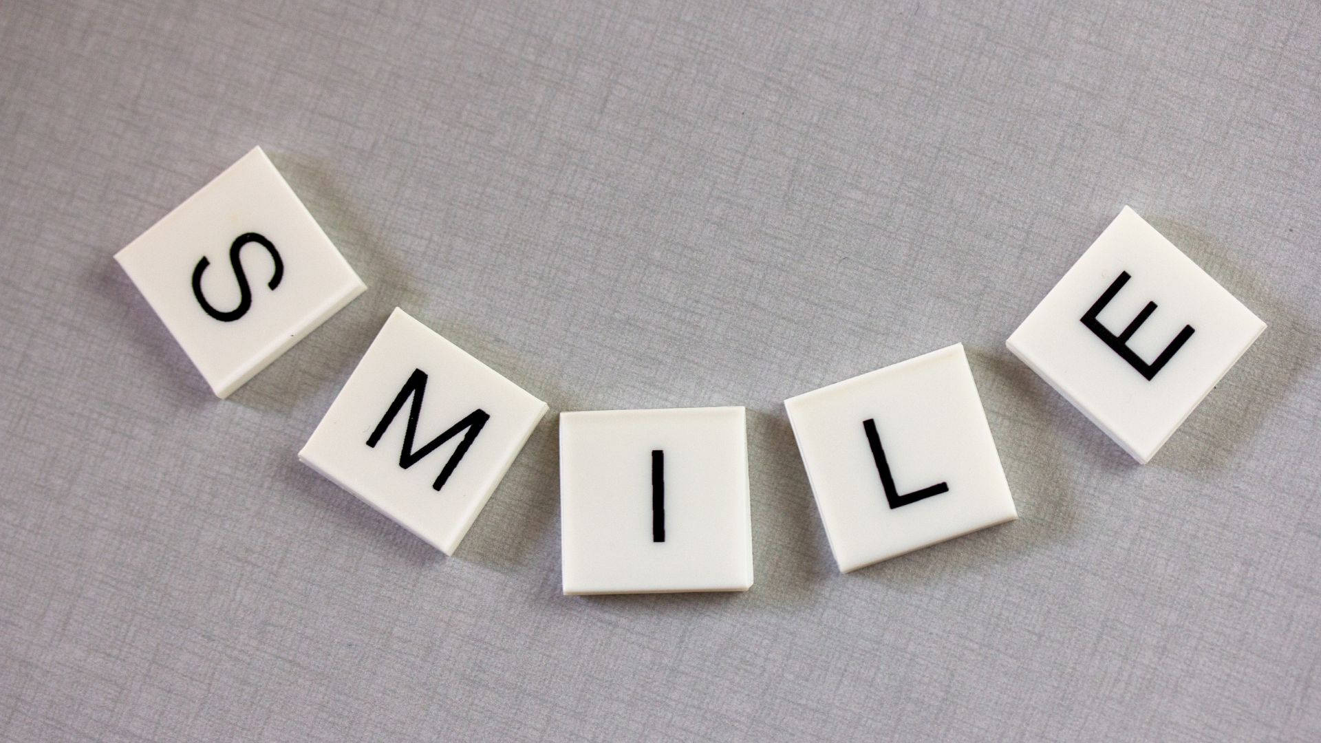 灰色布料上帶有黑色字母拼出 smile 的白色瓷磚。