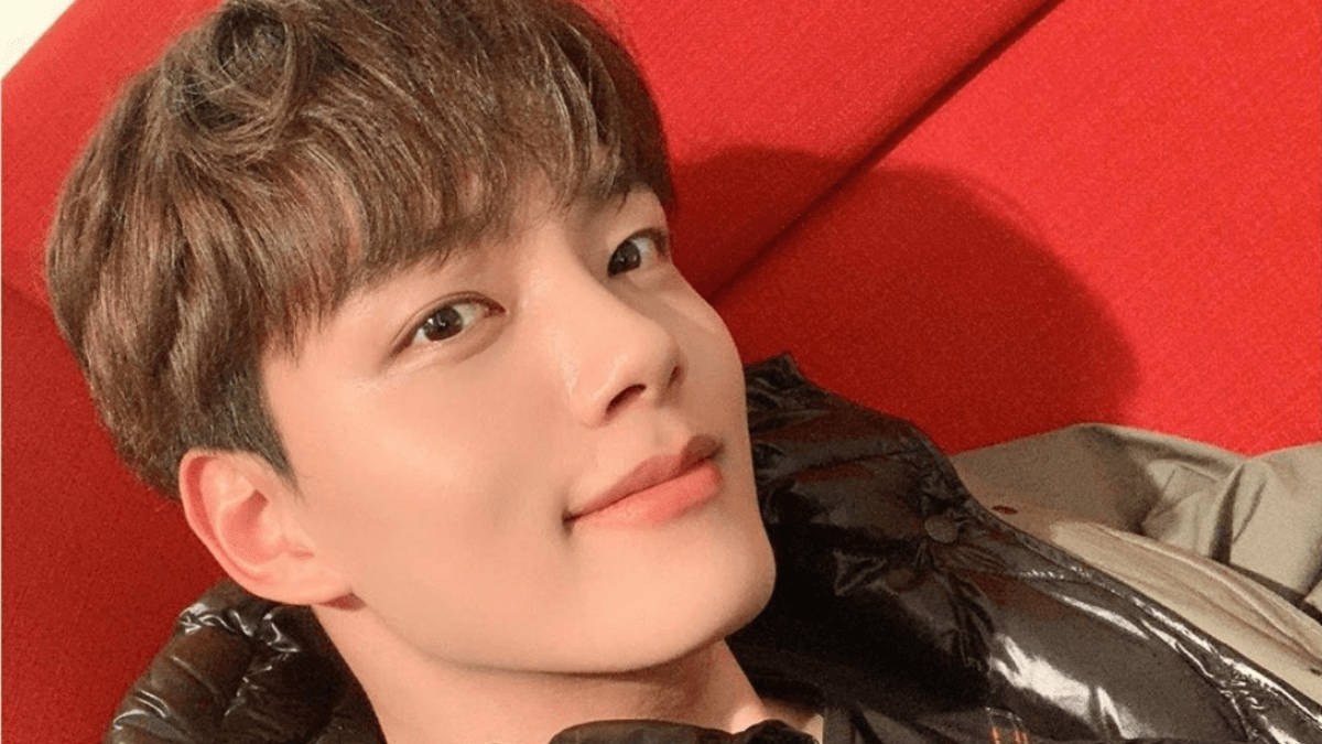微笑的 Yeo Jin Goo 壁紙 — 一位棕色頭髮的年輕男子微笑著，靠在一張鮮紅色的軟墊表面上。