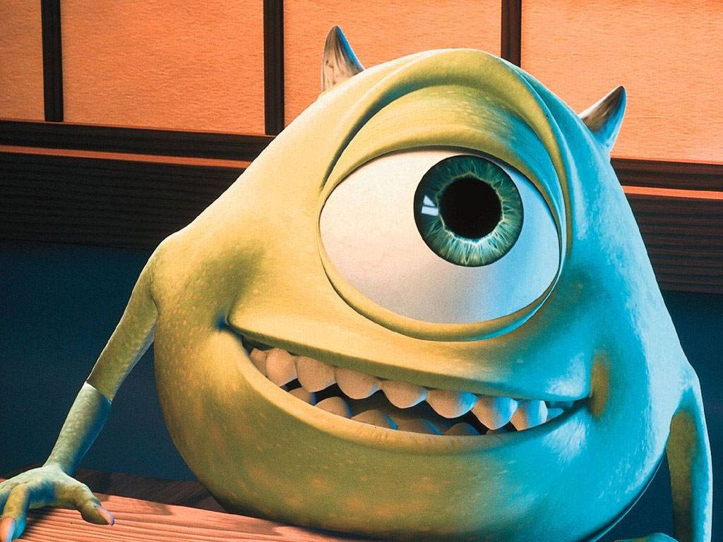 微笑的Mike Wazowski 壁紙 — 一隻快樂的綠色獨眼怪物，有著鋒利的牙齒和小角，在木質背景下溫暖地微笑。