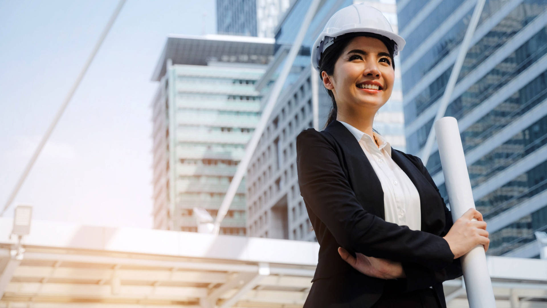 自信的女性建築師在現代建築前拿著藍圖。