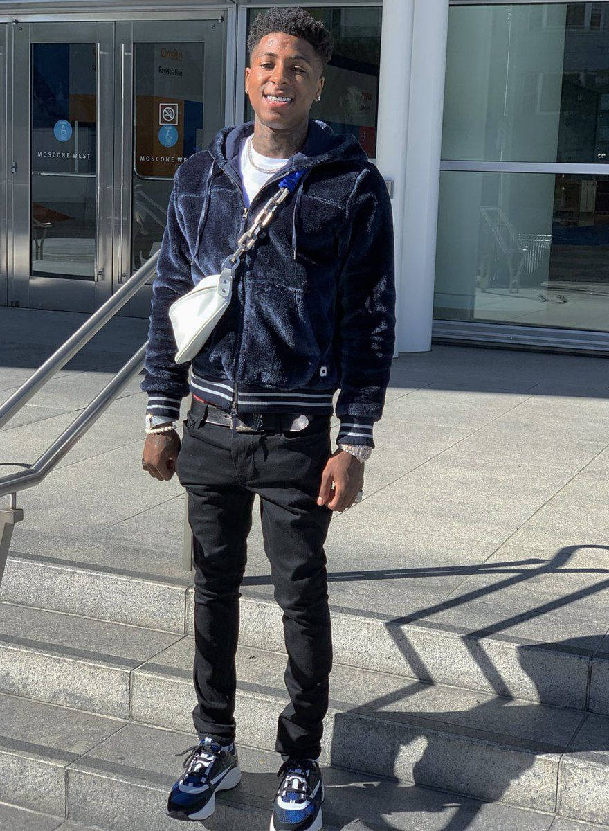街頭服飾的年輕男子在現代建築外的石階上微笑。