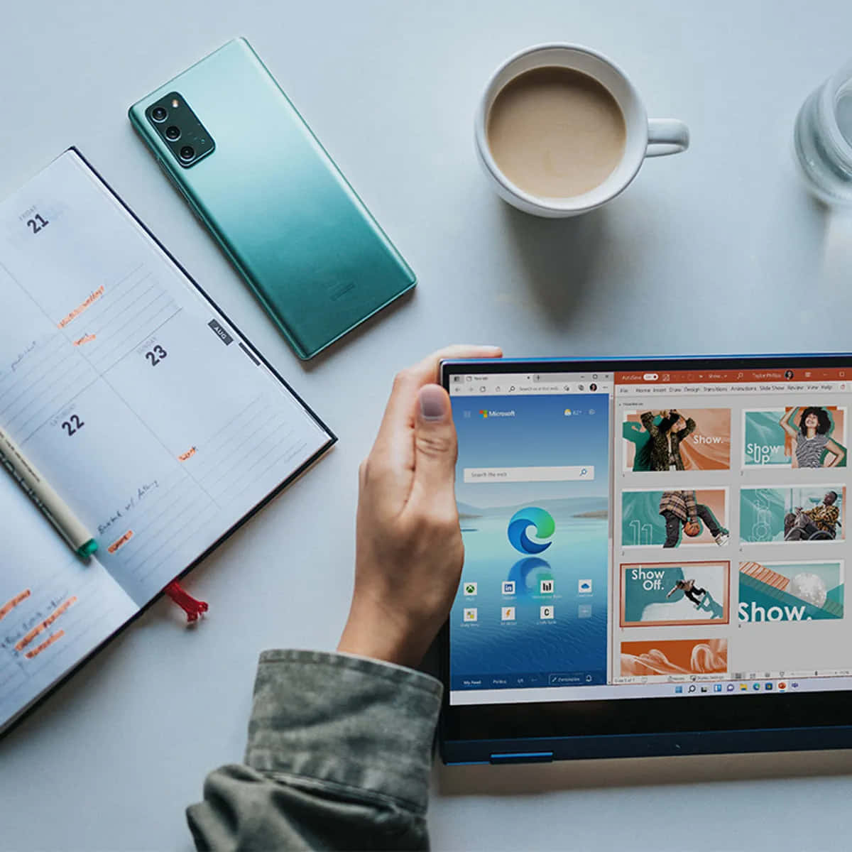 手拿著平板電腦，Microsoft Edge 已打開，旁邊有日曆、電話、咖啡和水在桌子上。
