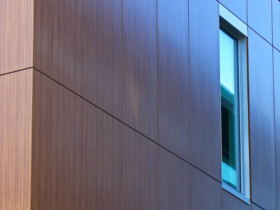 微軟Surface窗景 壁紙 — 現代建築外牆，採用溫暖木質面板和冷色調藍色金屬裝飾，配以狹窄的垂直窗戶。