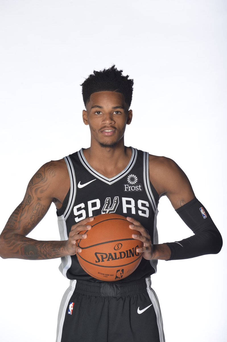 德容特·默里NBA媒體日 壁紙 — 一名身穿黑色馬刺球衣的籃球運動員，在純白色背景前拿著一個Spalding籃球。