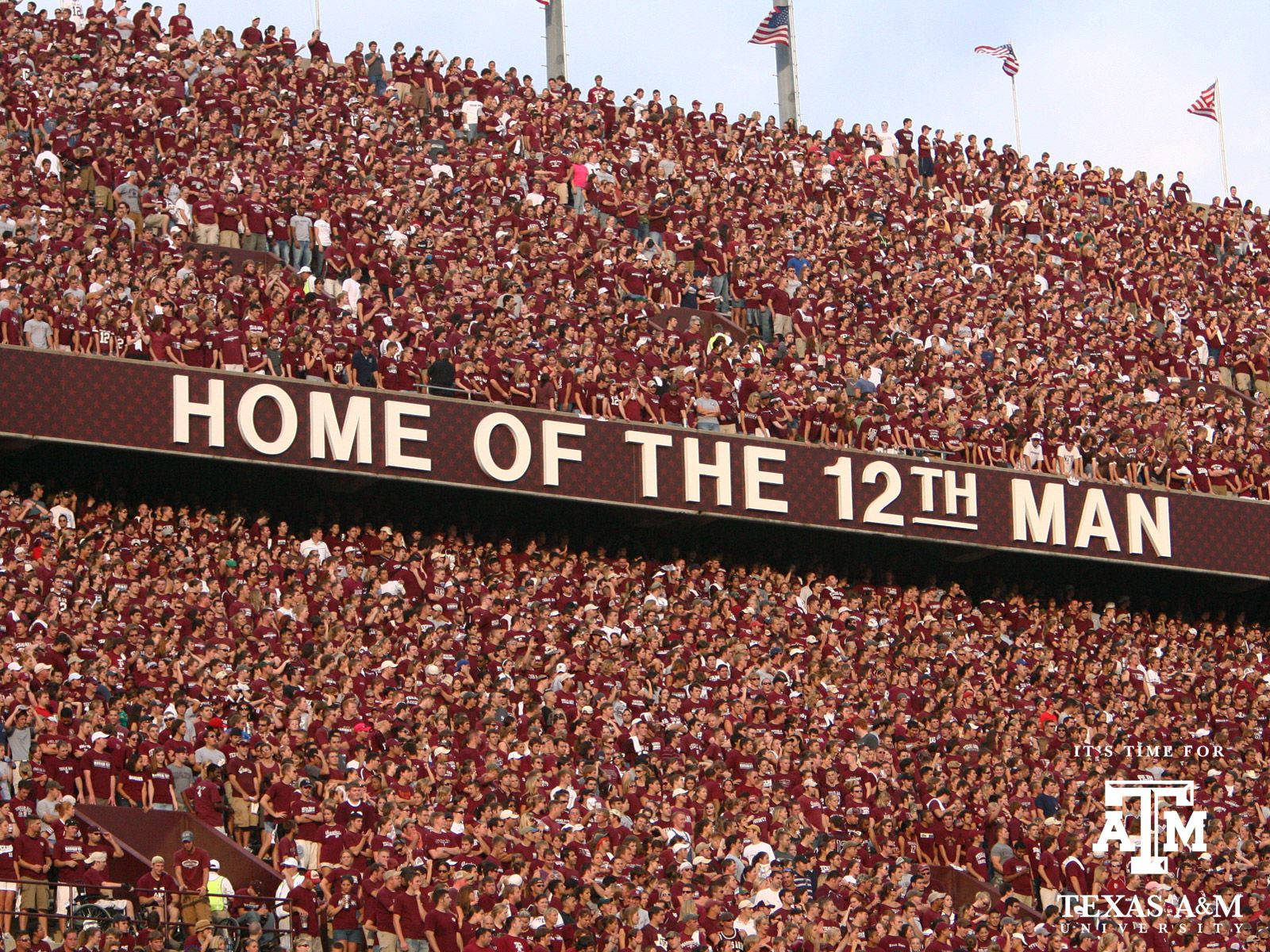 球場觀眾身穿栗色球衣在「Home of the 12th Man」標誌下歡呼。